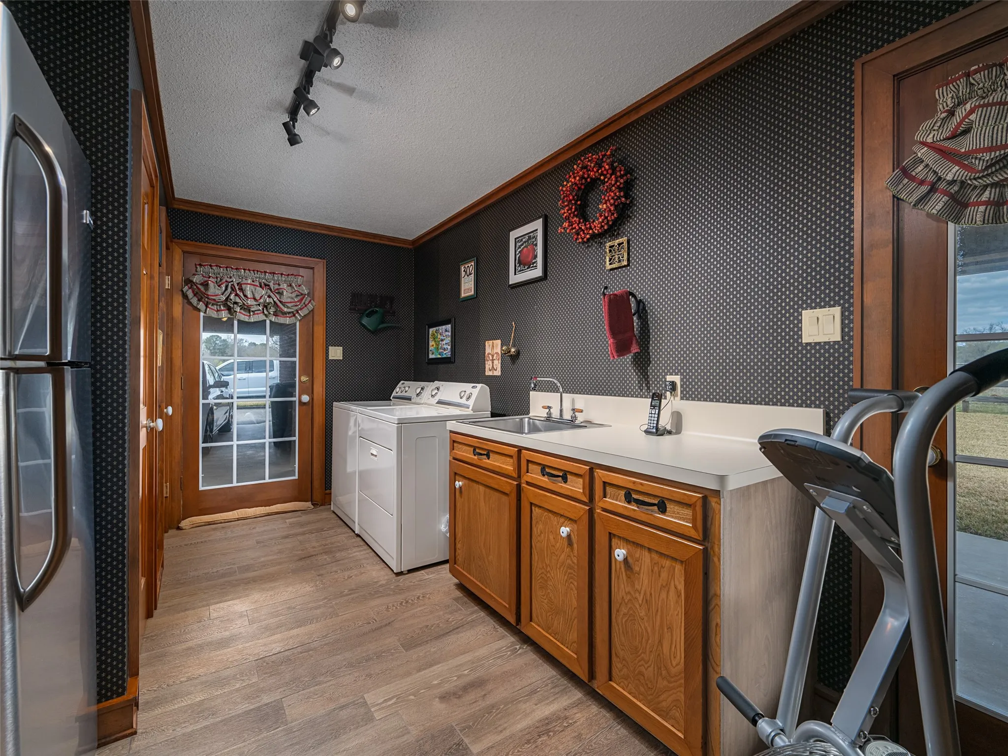 Room featuring wood-finish flooring, a utility sink with a countertop, and wood cabinetry