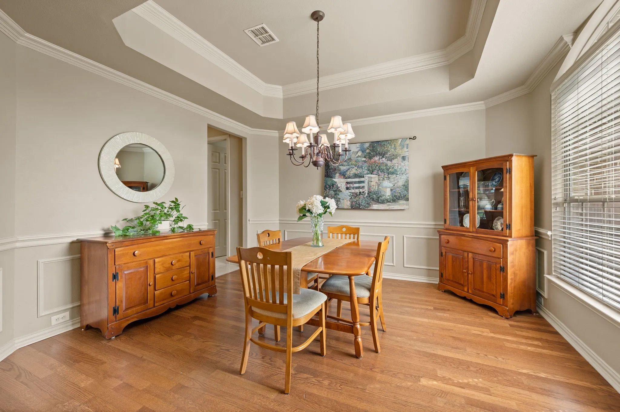Wood-finish flooring, tray ceiling, crown molding, chair rail molding, and a chandelier