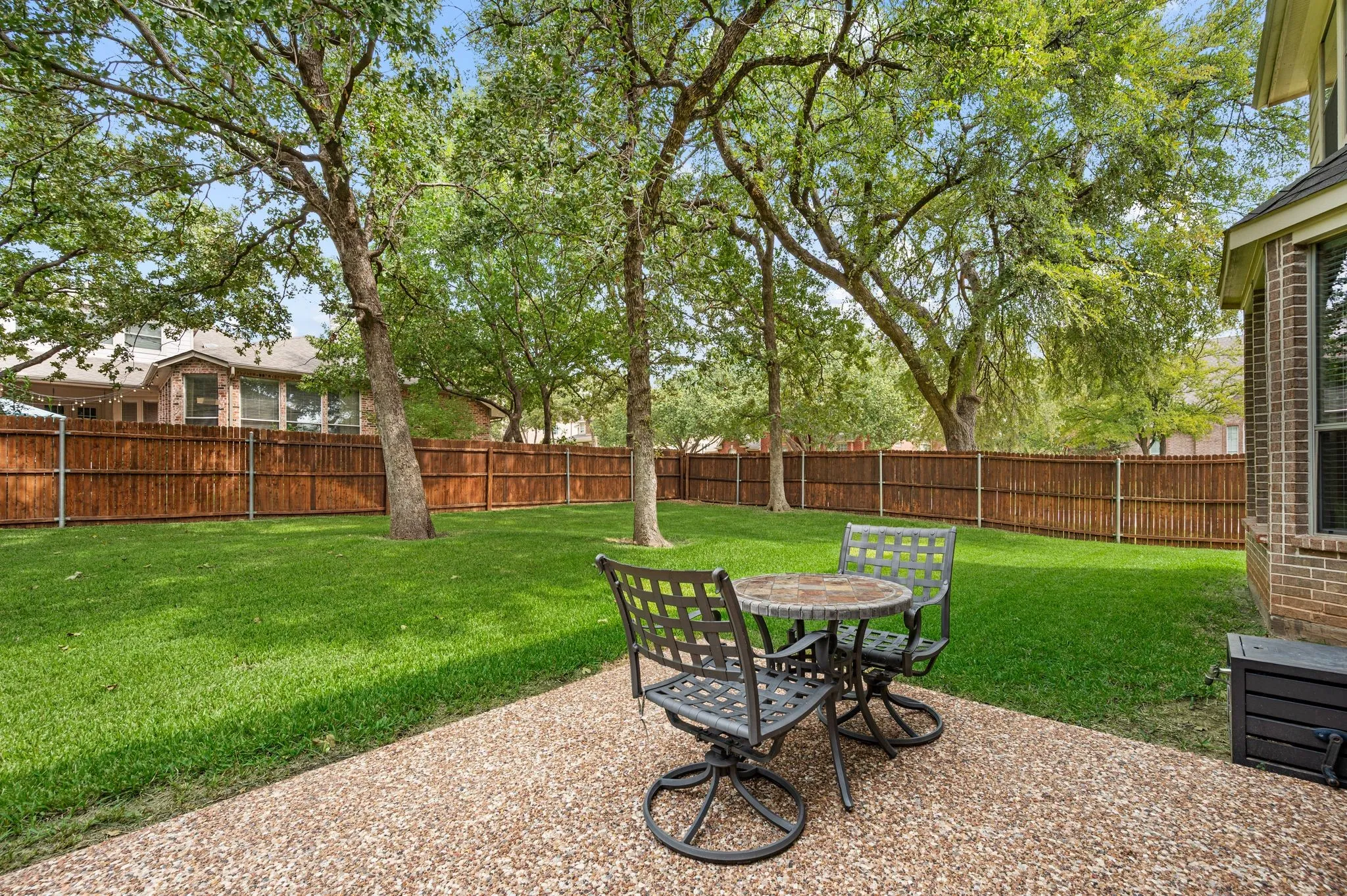 Expansive backyard featuring a large grass lawn, mature trees, and a wooden privacy fence
