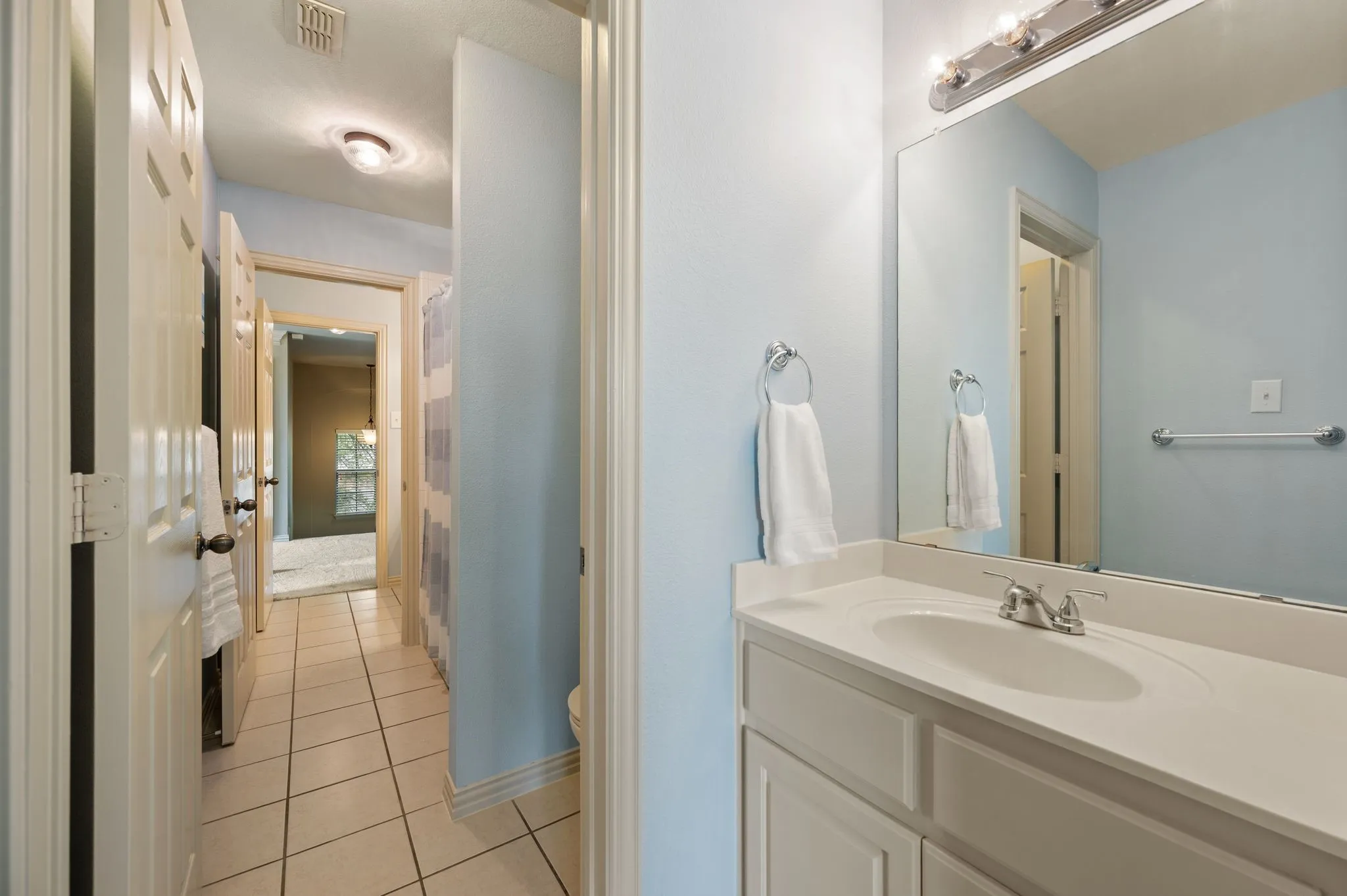 Single vanity with integrated sink, chrome faucet, and overhead bar lighting