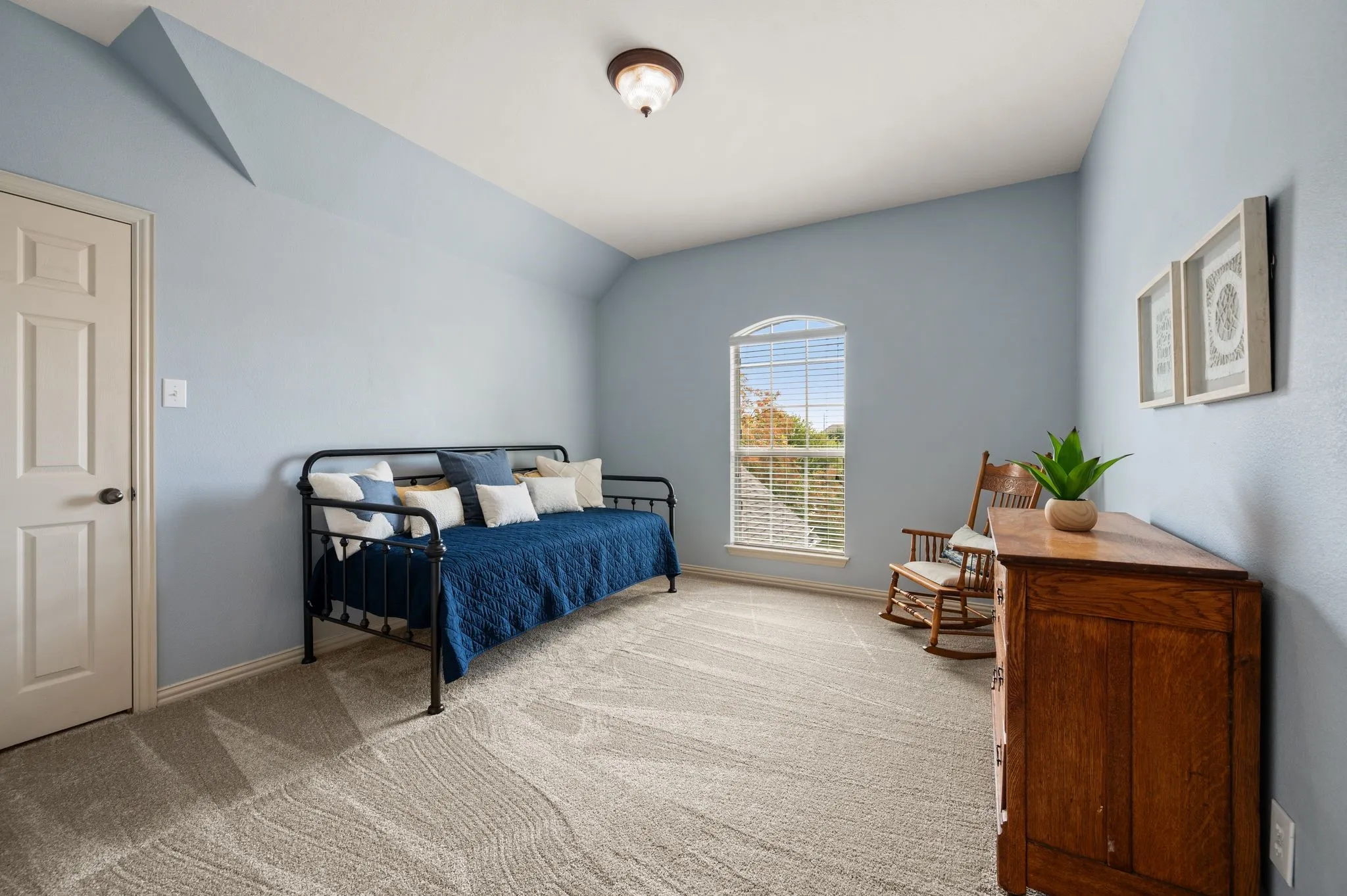Arched window with blinds, plush patterned carpeting, ceiling-mounted light fixture, paneled interior door, and sloped ceiling