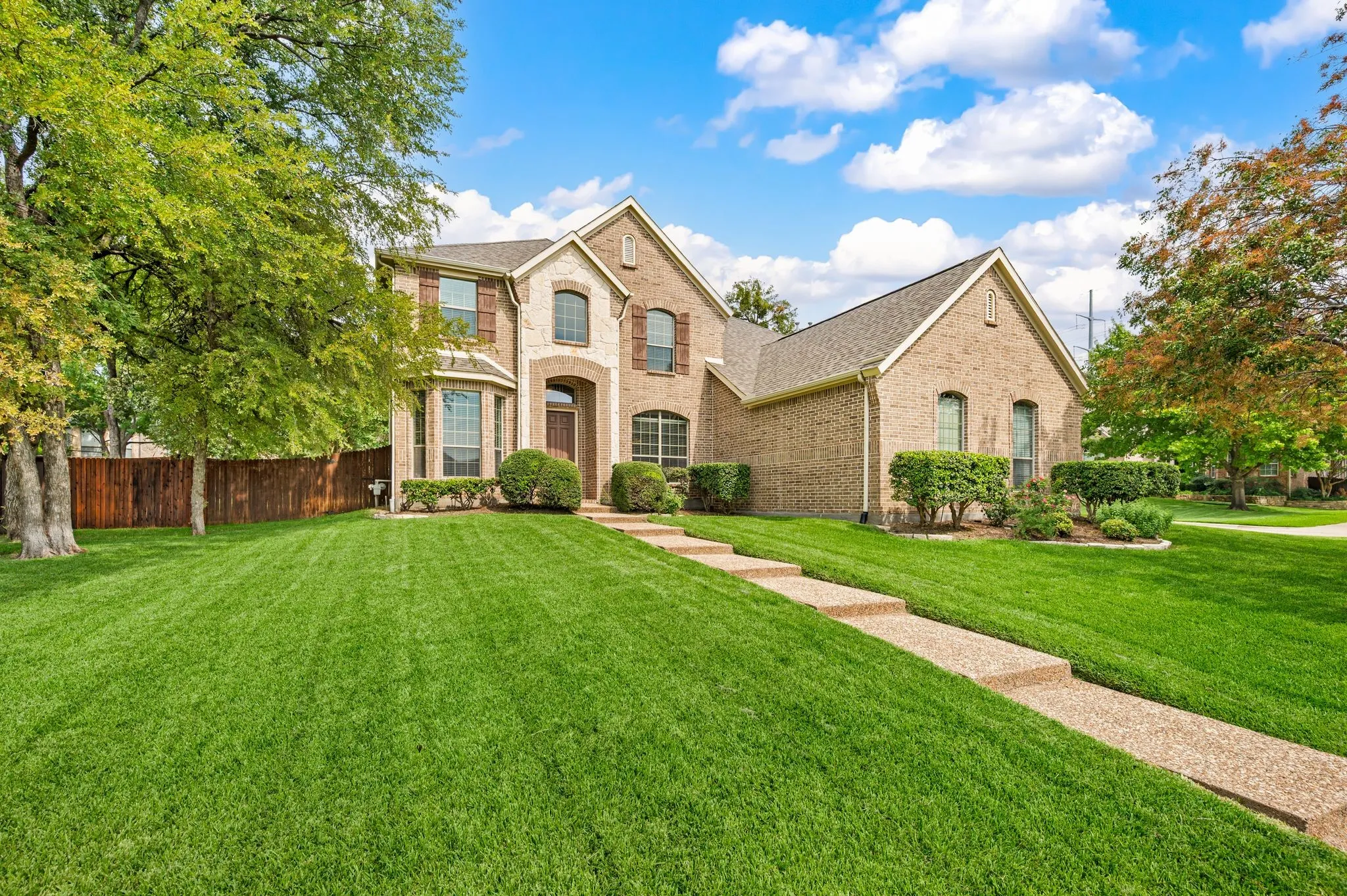 Brick exterior with stone accents, mature landscaping, multi-level entry, arched windows, and a segmented pathway