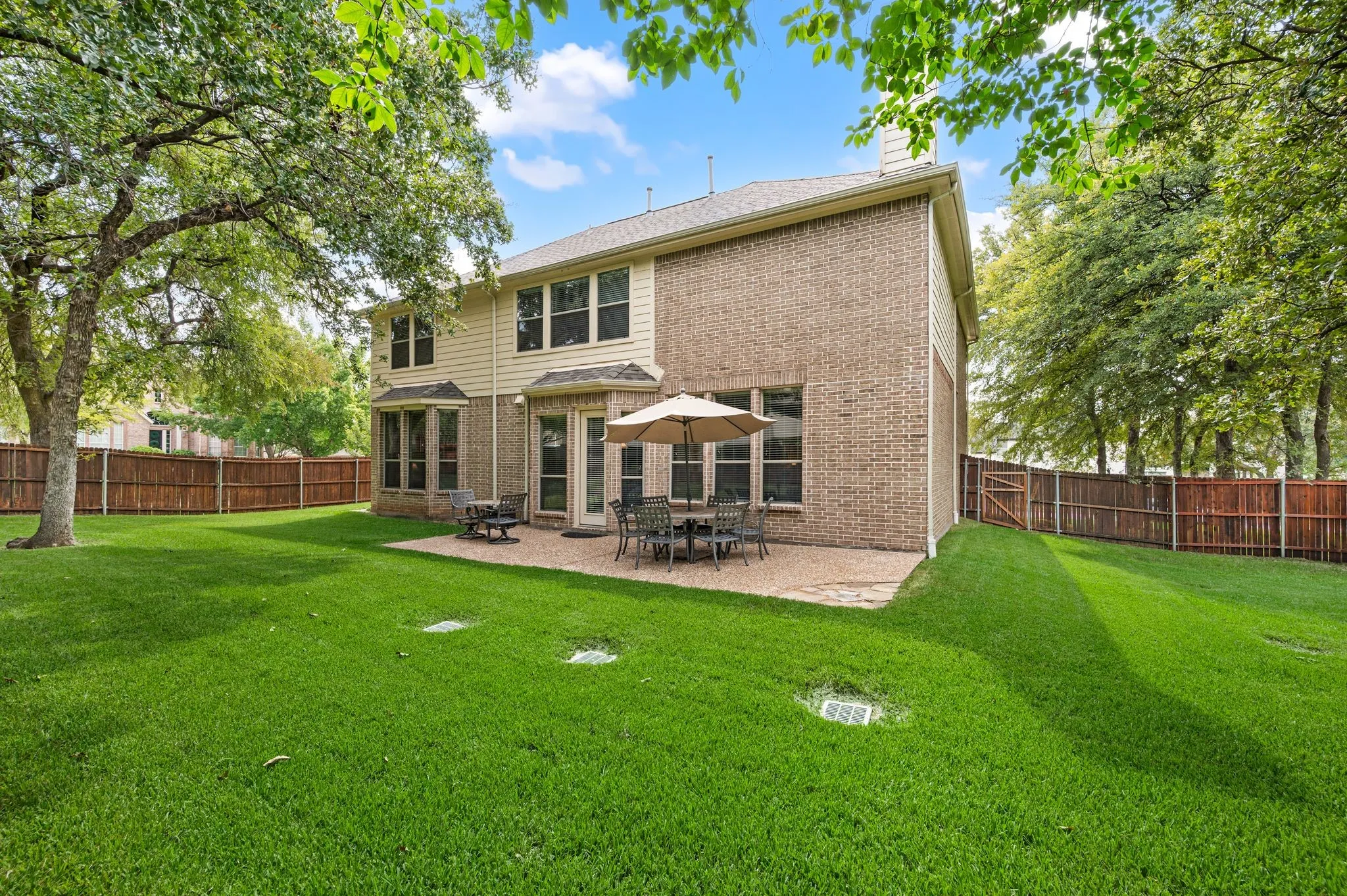 Expansive green lawn, mature trees, and a private wood fence