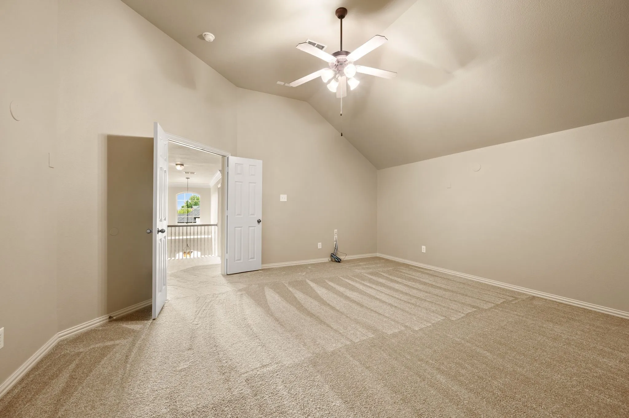 Vaulted ceiling featuring a ceiling fan with integrated lighting, neutral wall paint, and plush carpeting