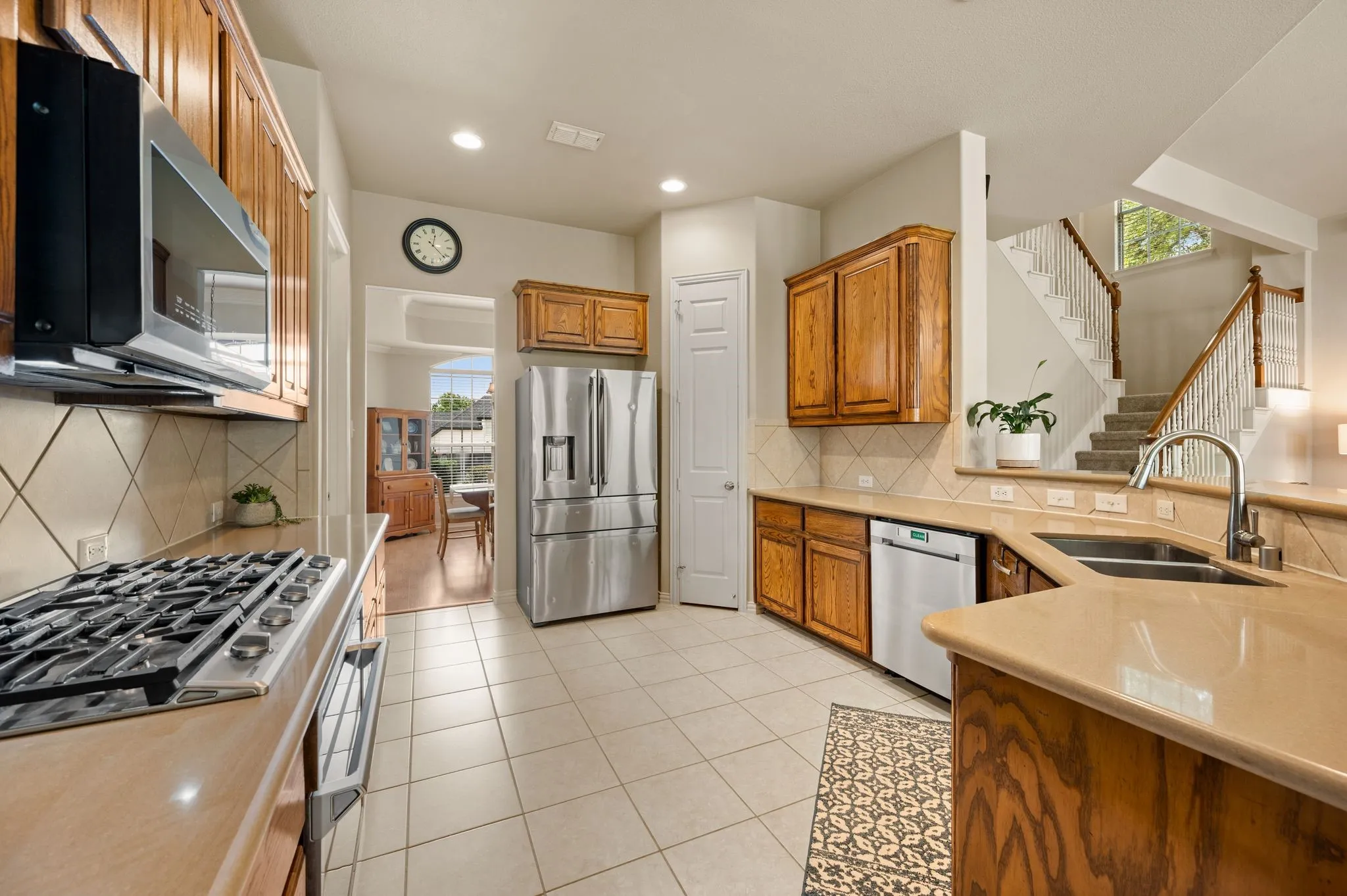 Kitchen featuring wood cabinetry, stainless steel appliances, tile flooring, and solid surface countertops