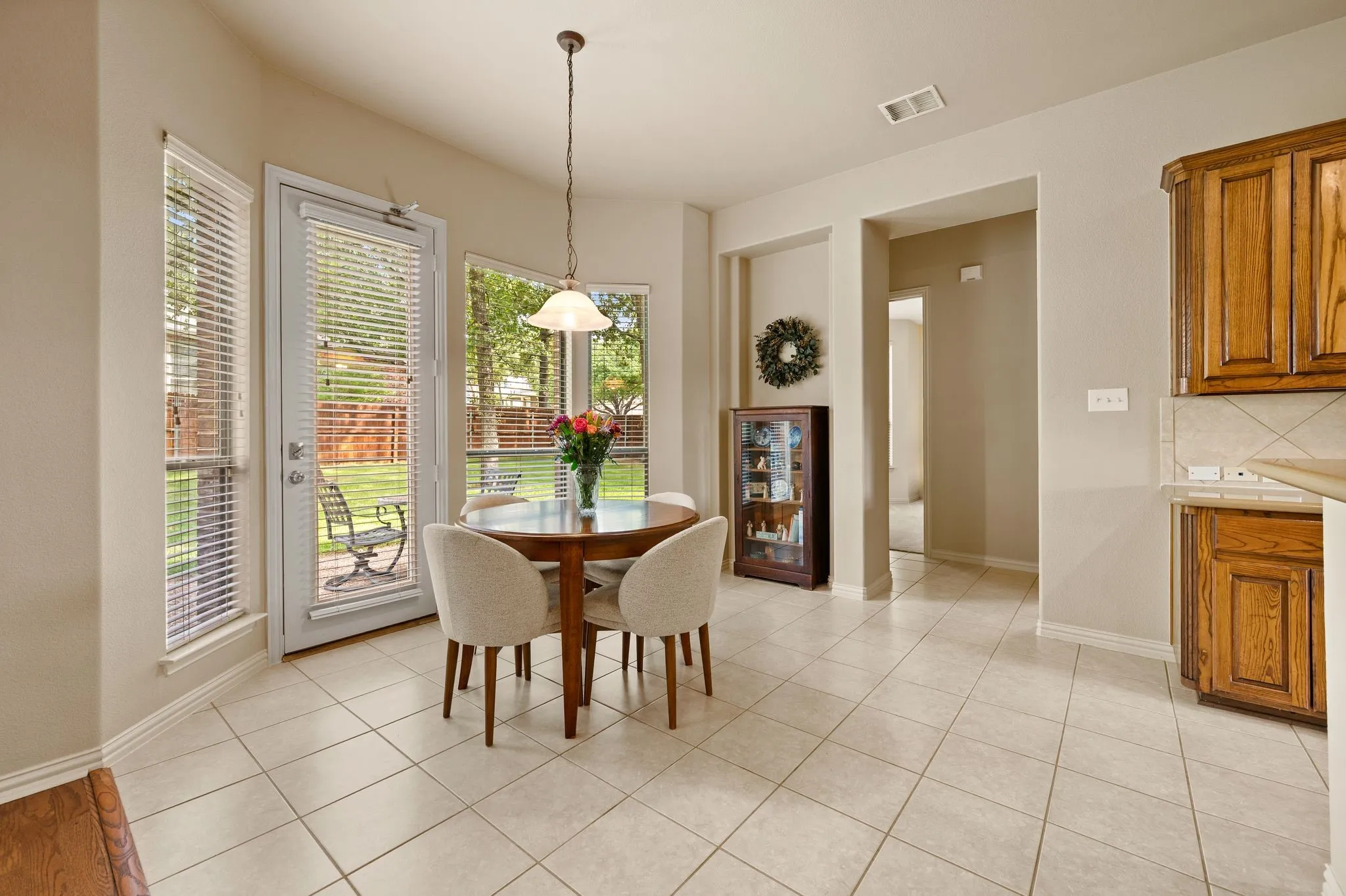 Tile flooring extending into an archway, warm wood-finish cabinetry, built-in shelving, and a pendant light fixture