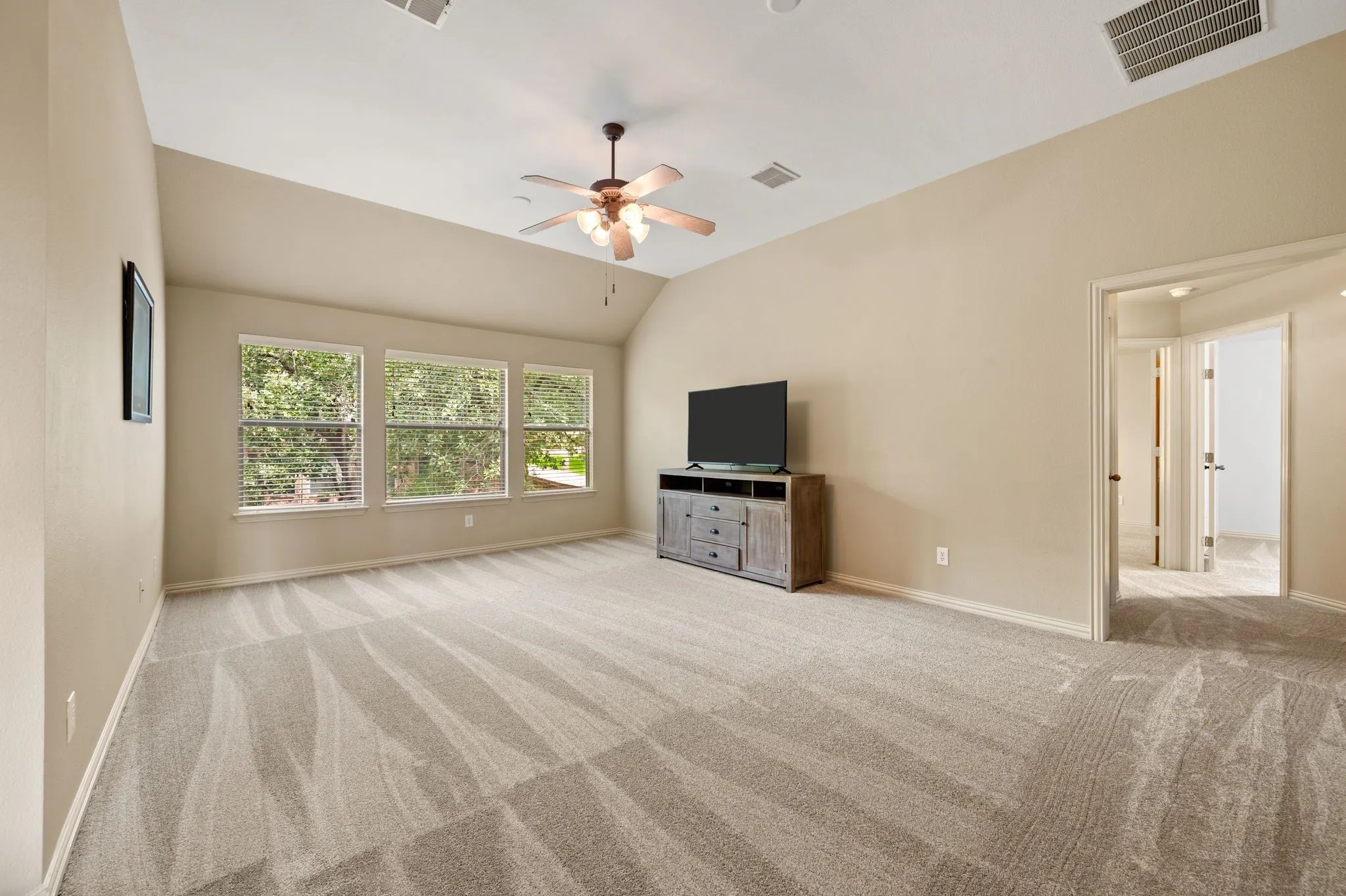 Spacious room featuring vaulted ceilings, recessed lighting, a ceiling fan, and multiple windows