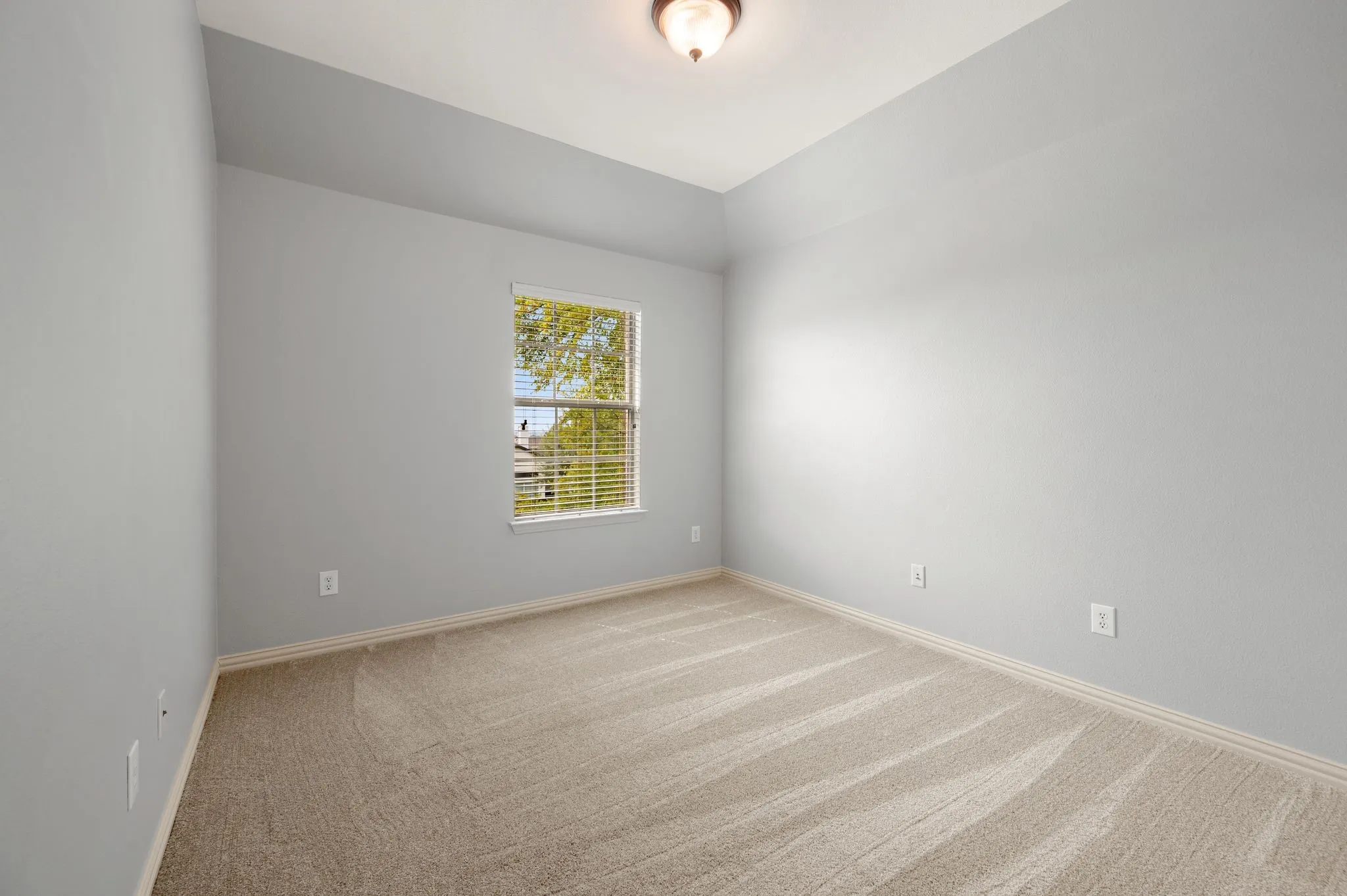 Tray ceiling with an overhead light fixture, light gray wall paint, and neutral tone carpet flooring