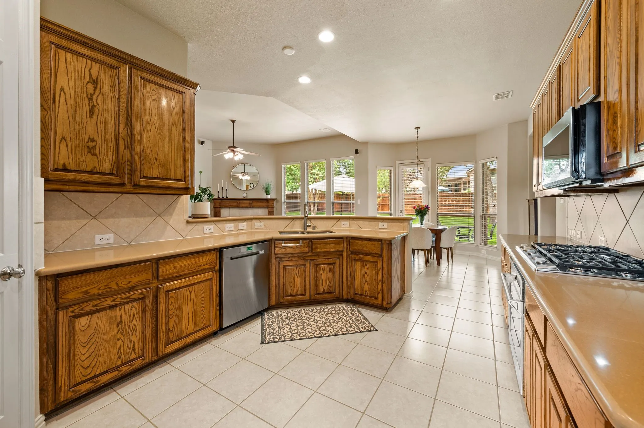 Kitchen featuring wood cabinetry, light-toned countertops, a tile backsplash, and stainless steel appliances