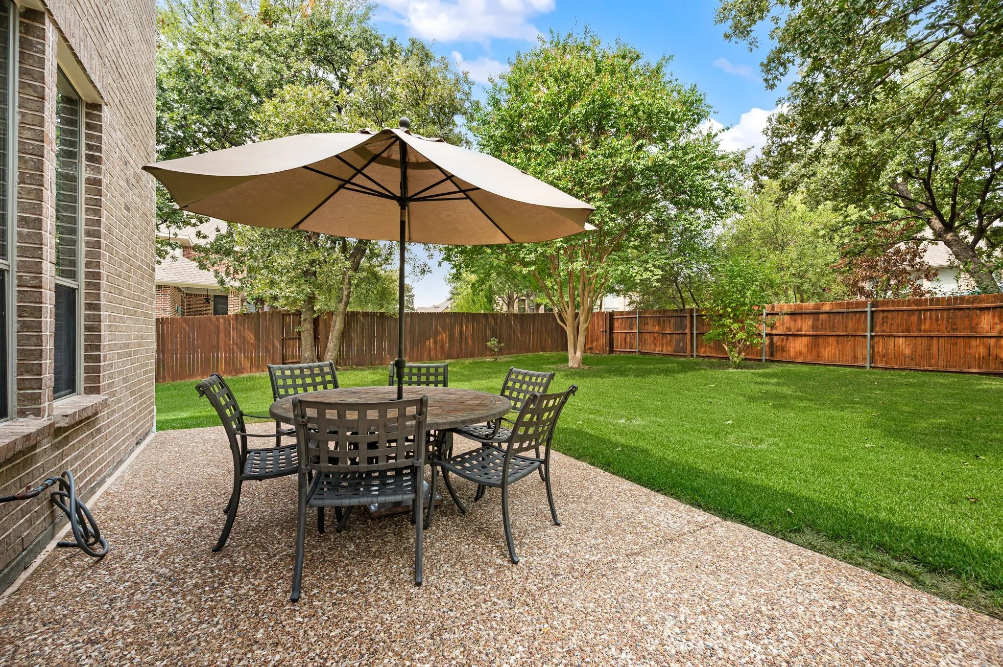 Expansive backyard featuring a manicured lawn, wood fencing, and mature trees