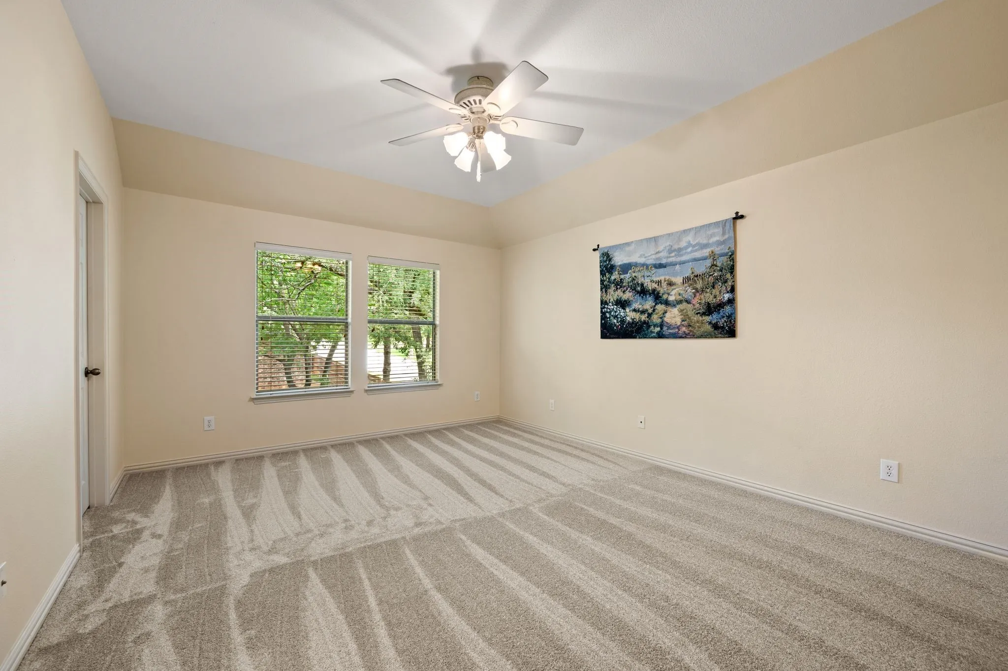 Vaulted ceiling with a ceiling fan, dual windows, and plush carpet flooring