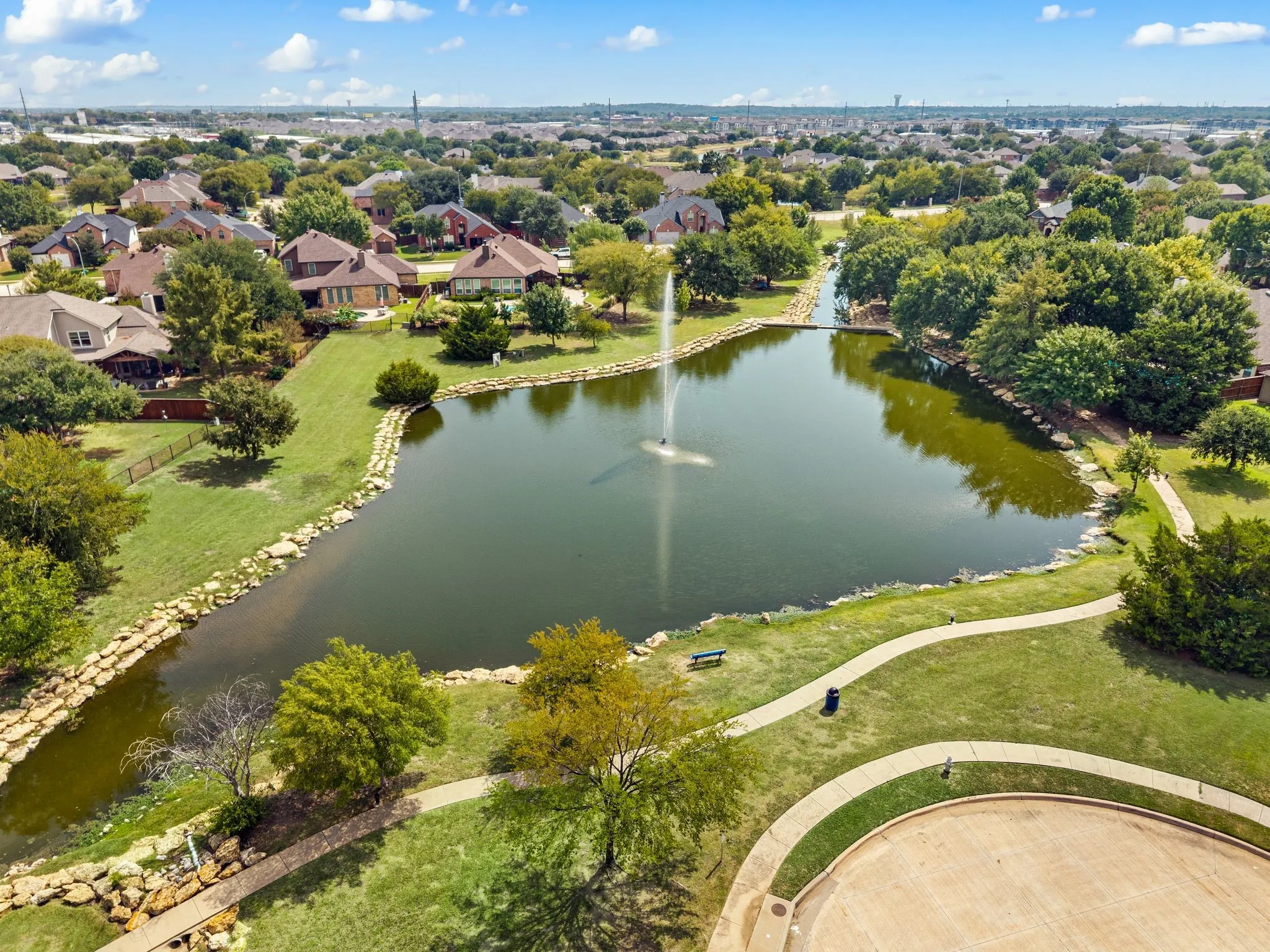 Expansive community pond featuring a central fountain and stone-lined banks