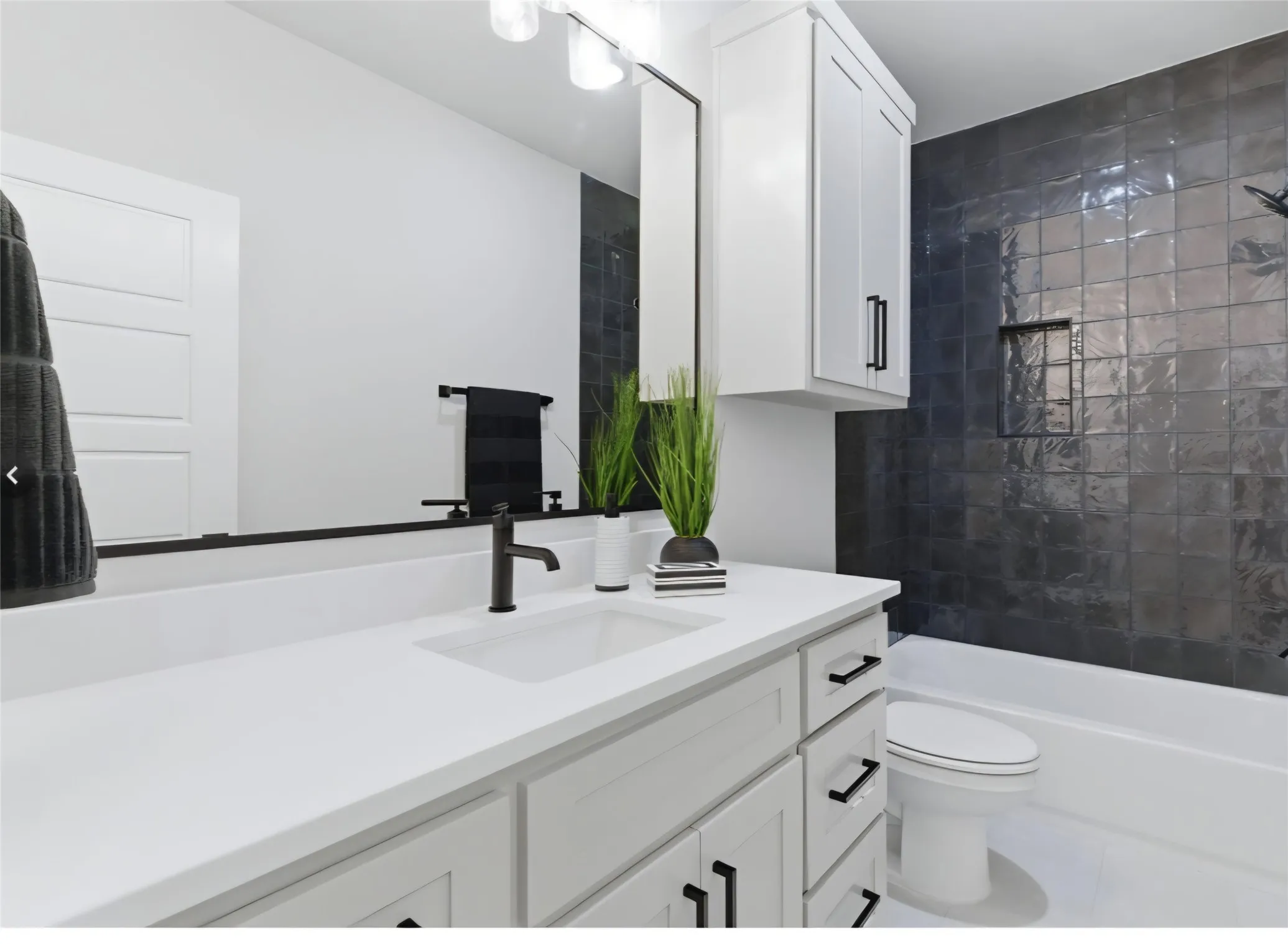 White vanity with black hardware, integrated sink, and matte black faucet