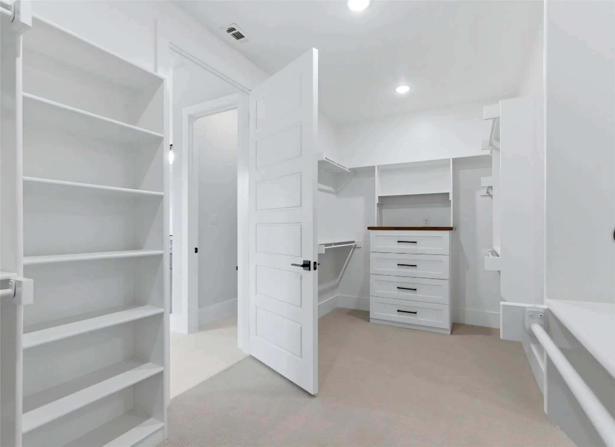 Custom closet system featuring built-in shelving, integrated drawers with dark hardware, and carpet flooring