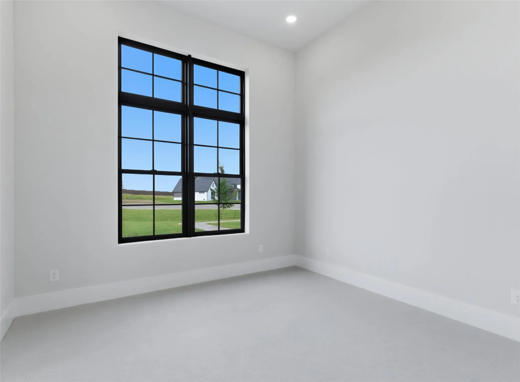 Large window with black grid, recessed ceiling lighting, light gray wall paint, and light gray carpet flooring