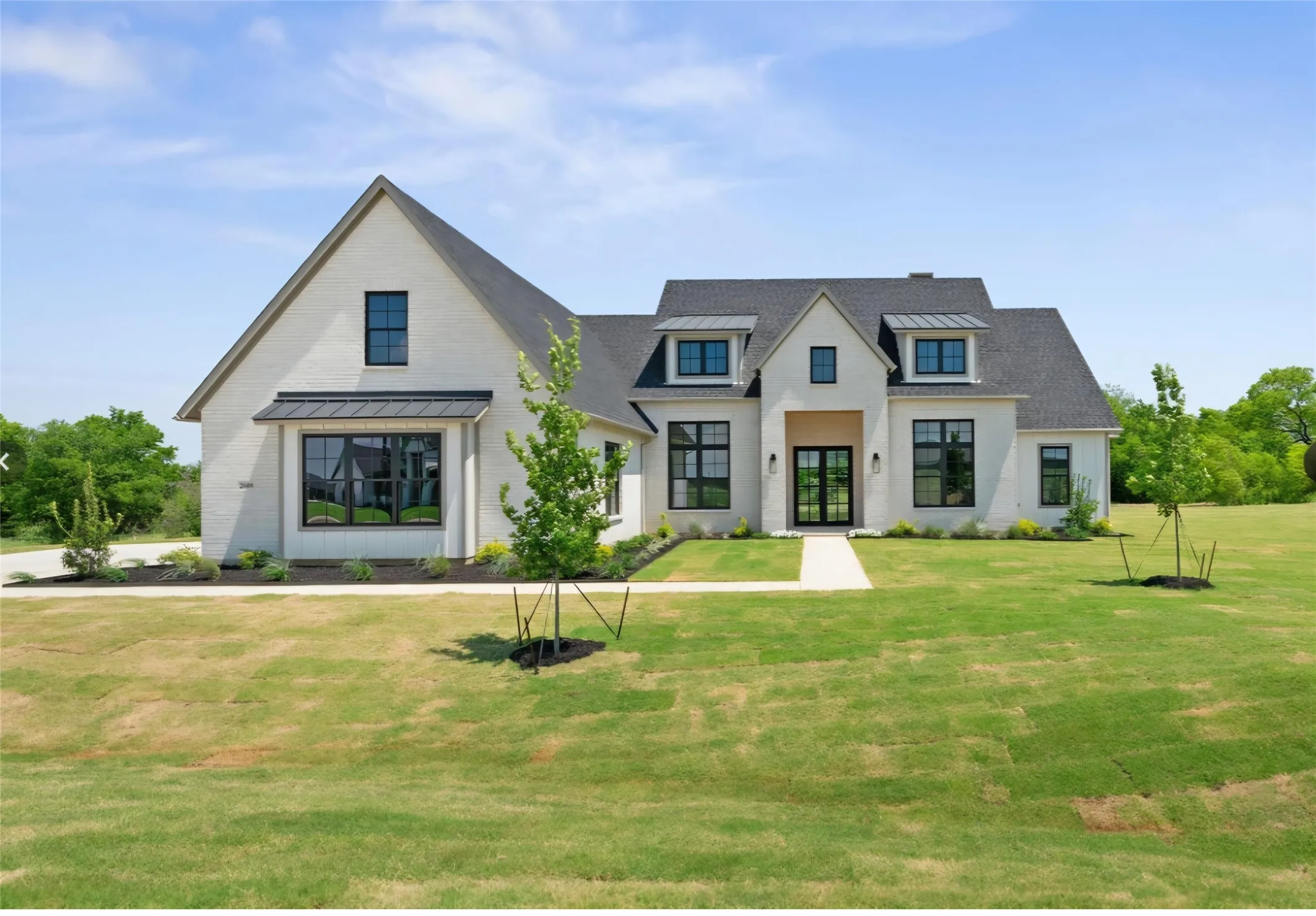 White brick exterior with a dark shingle roof, black-framed windows, and an arched entry