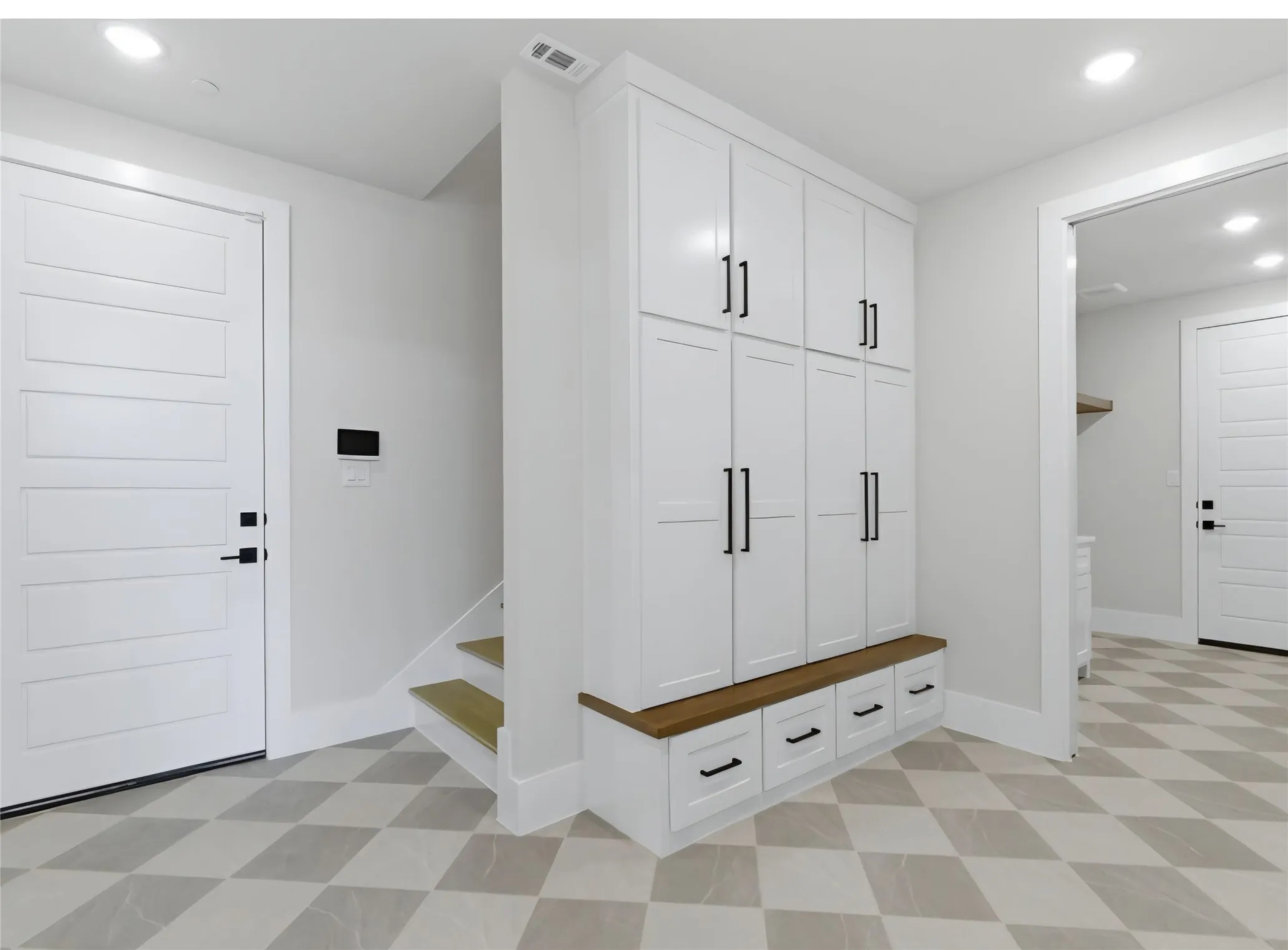 Built-in storage cabinetry with a wood-finish benchtop, contrasting matte black hardware, and patterned floor tile