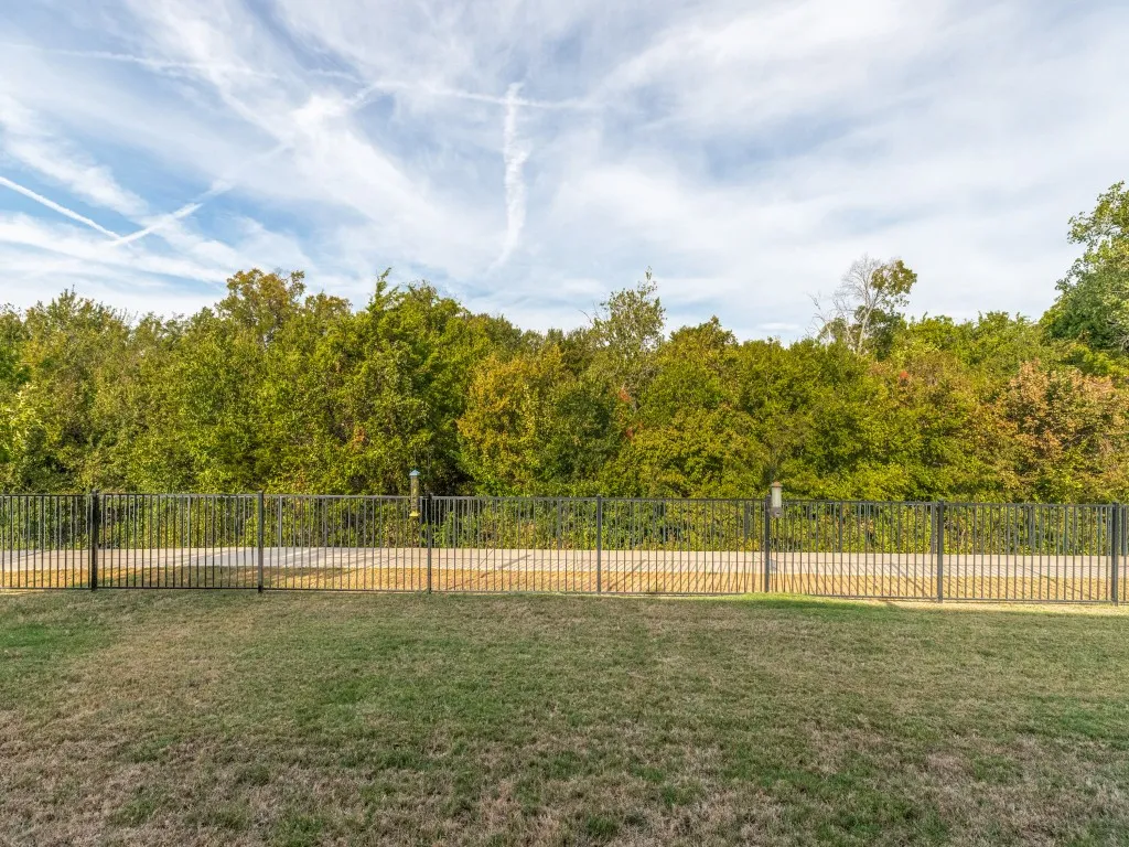 Expansive backyard featuring a manicured lawn and black metal fencing