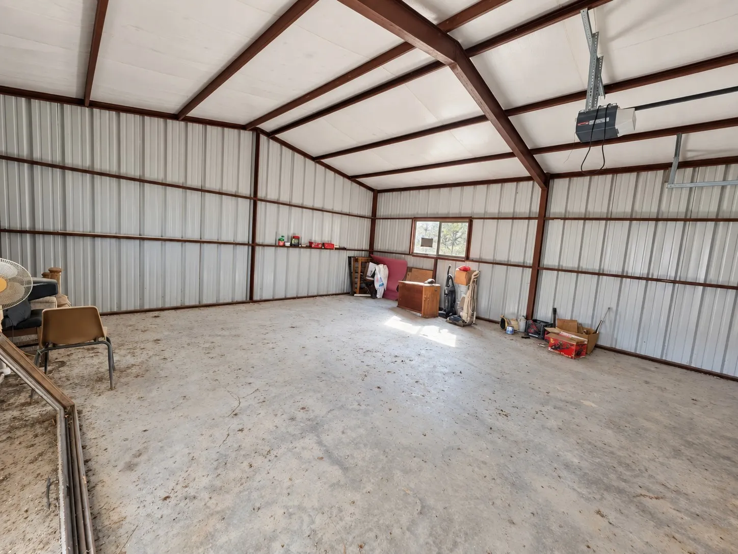 Metal-sided structure with exposed beam ceiling, concrete flooring, and an integrated window