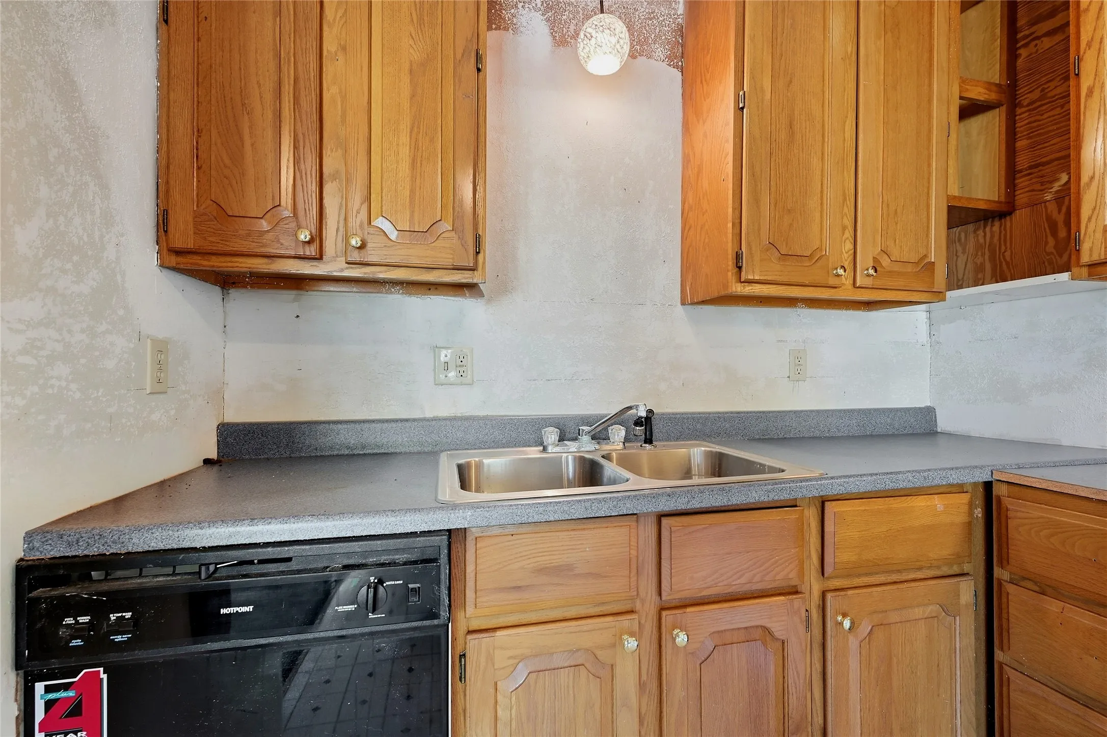 Kitchen featuring wood-finish cabinetry, a double basin stainless steel sink, black dishwasher, and laminate countertops