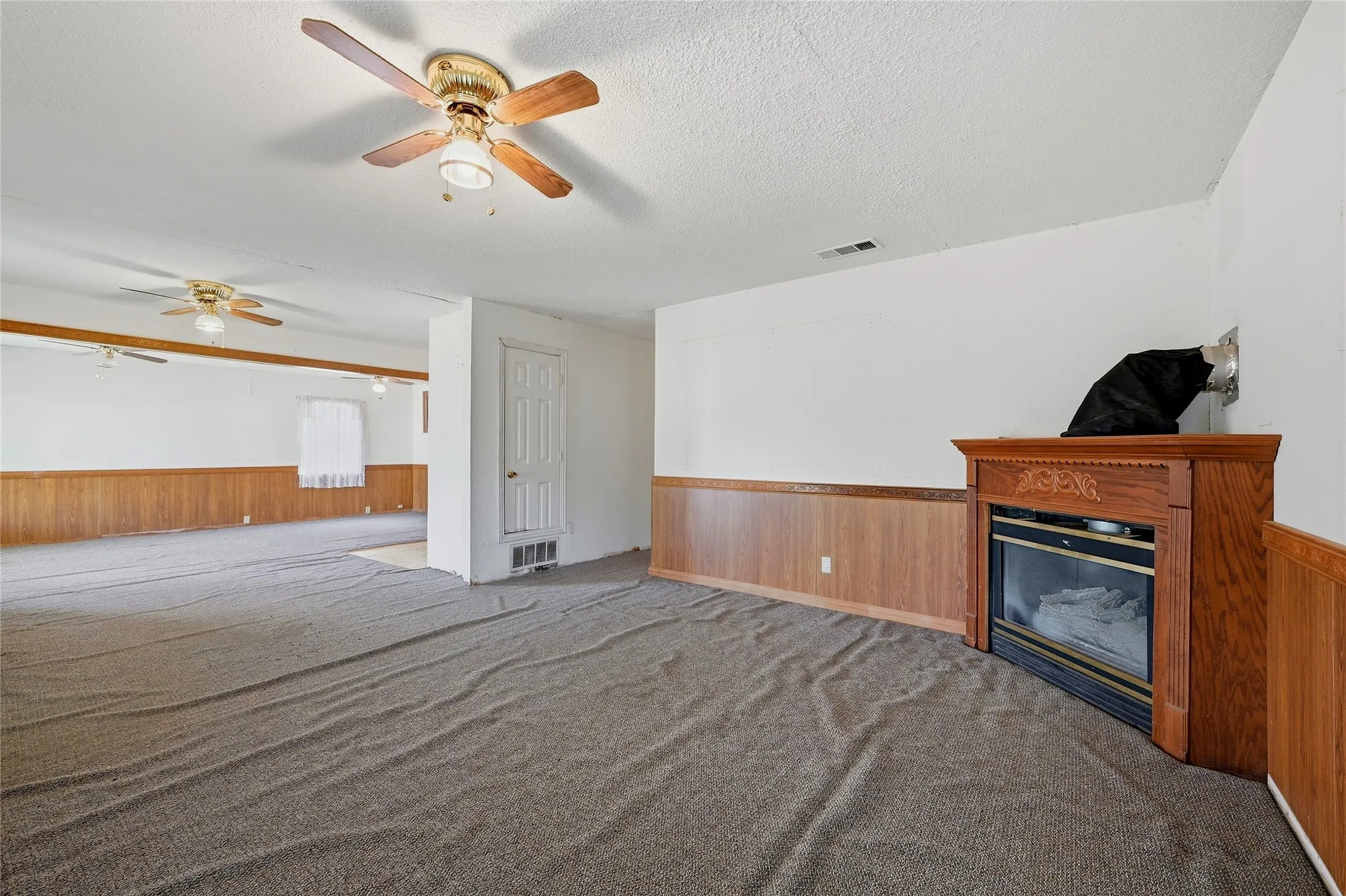 Wood-panel wainscoting, a built-in electric fireplace, and ceiling fans with integrated lighting