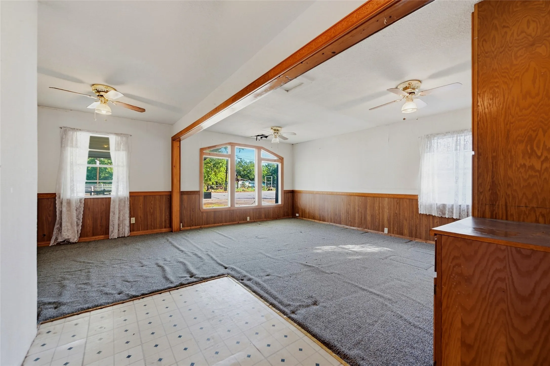 Spacious interior featuring a wood-paneled accent wall, multiple windows, and ceiling fans