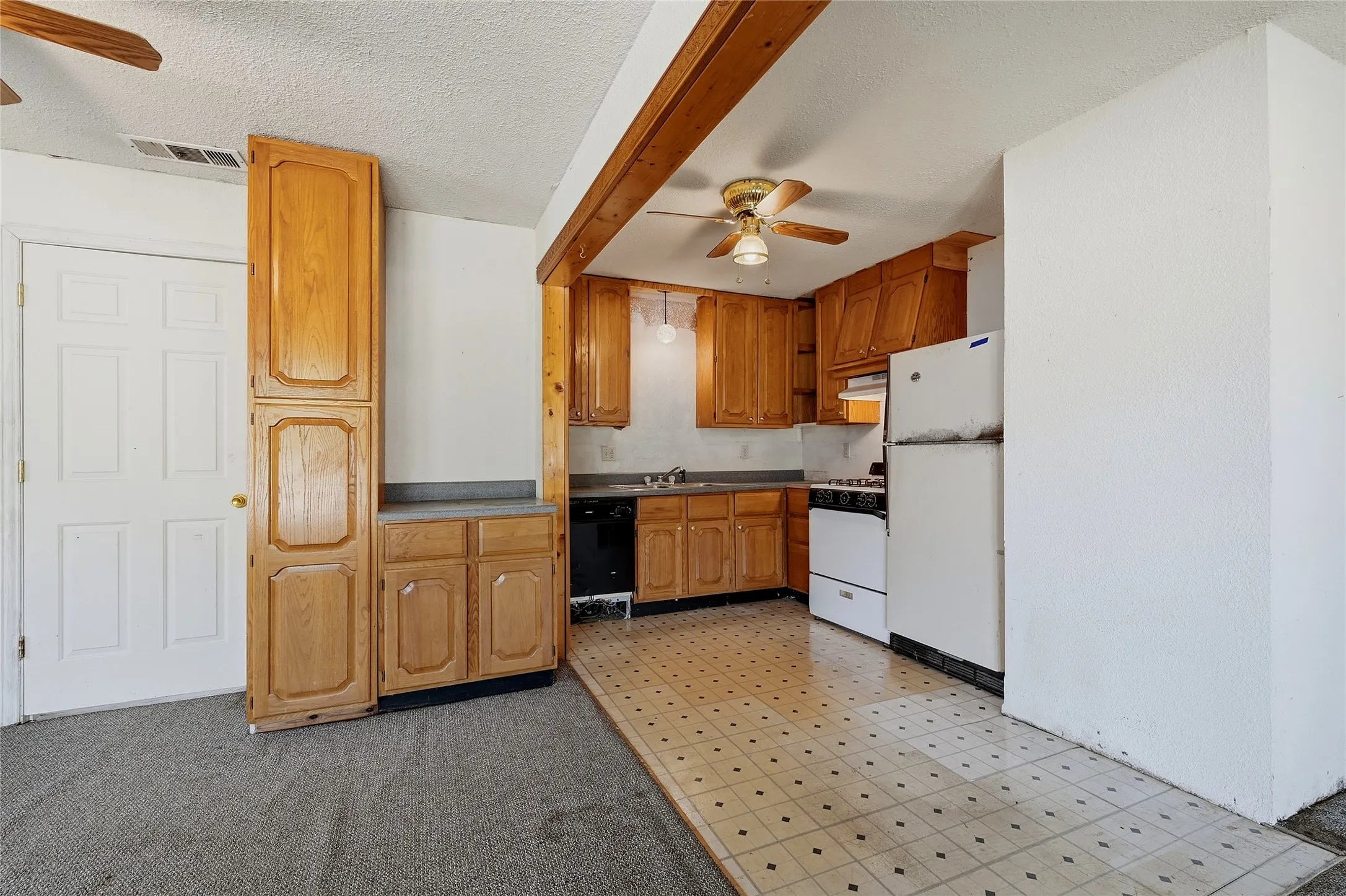 Full kitchen with wood-finish cabinetry, black dishwasher, and white refrigerator