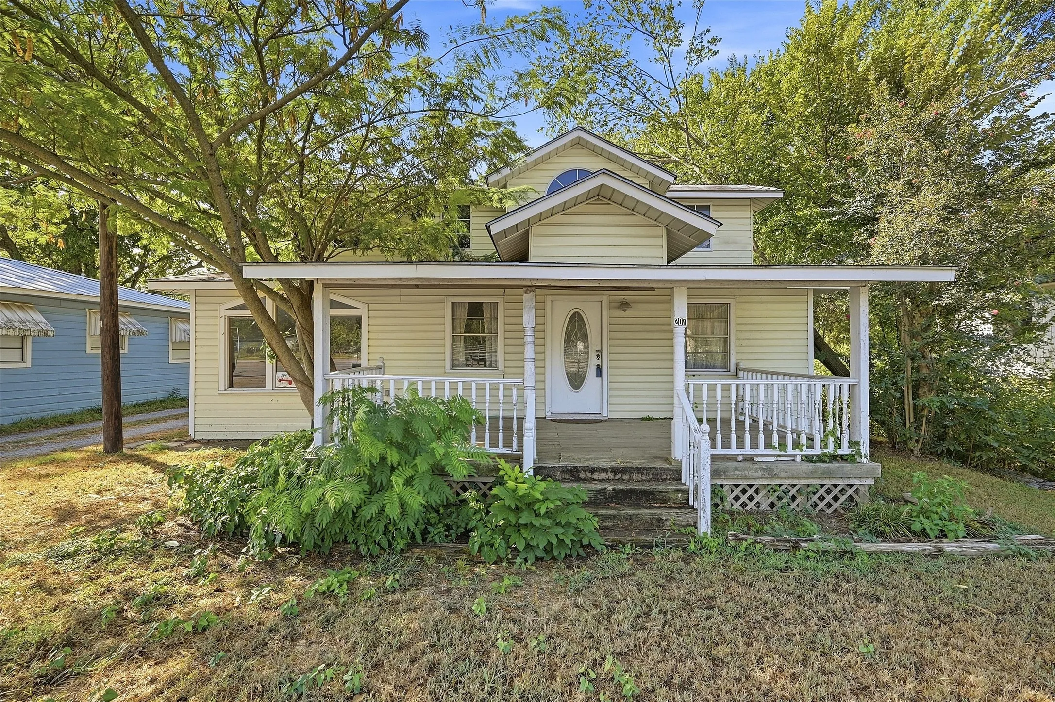 Front porch with white railings, a partial upper level, and an oval lite entry door