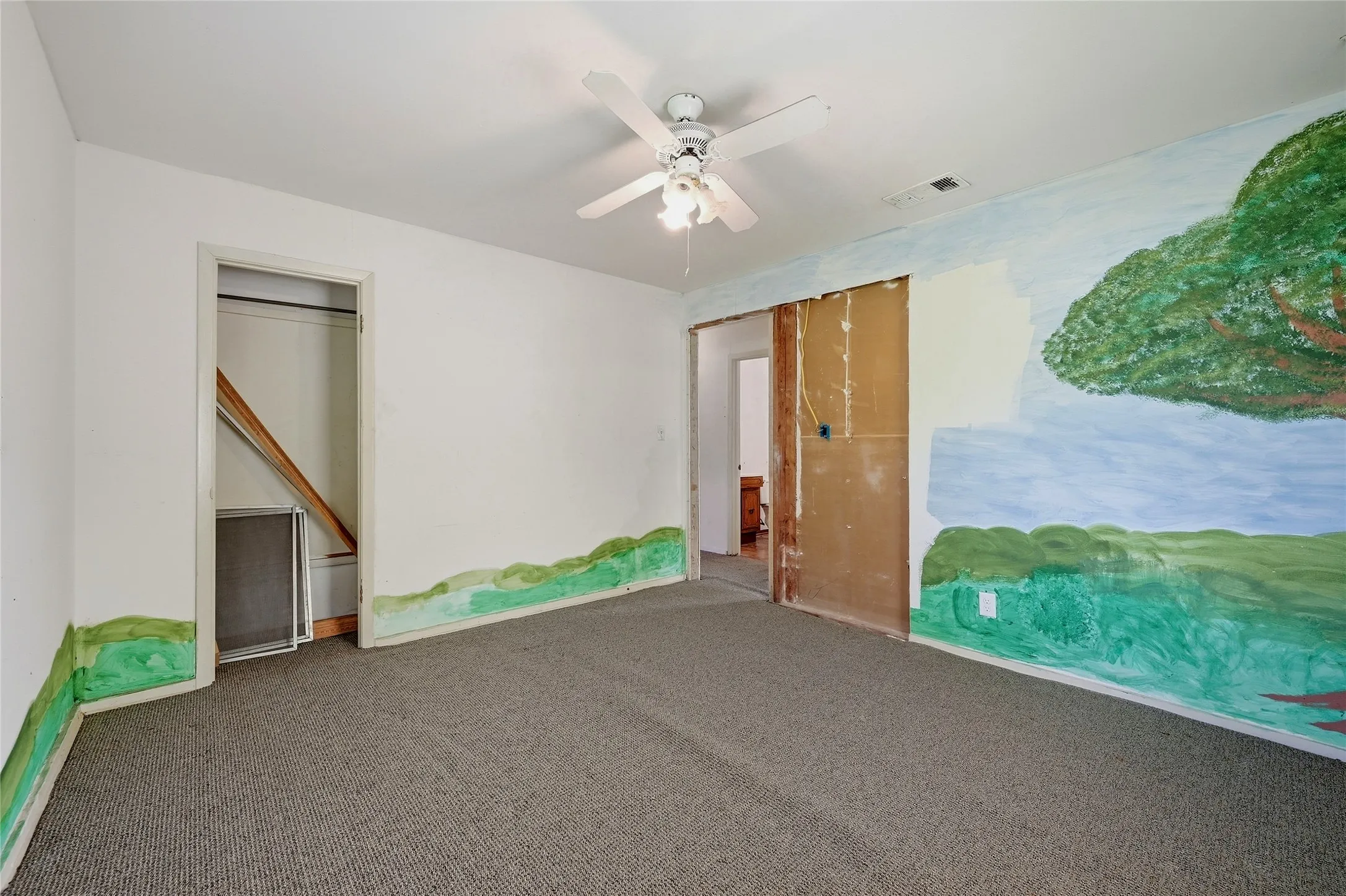 Carpeted flooring, ceiling fan with integrated lighting, wall murals, and recessed doorway