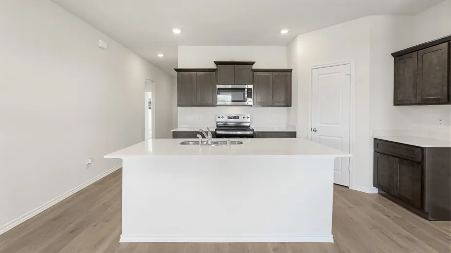 Kitchen featuring a large central island, stainless steel appliances, dark wood-finish cabinetry, and light wood-finish flooring