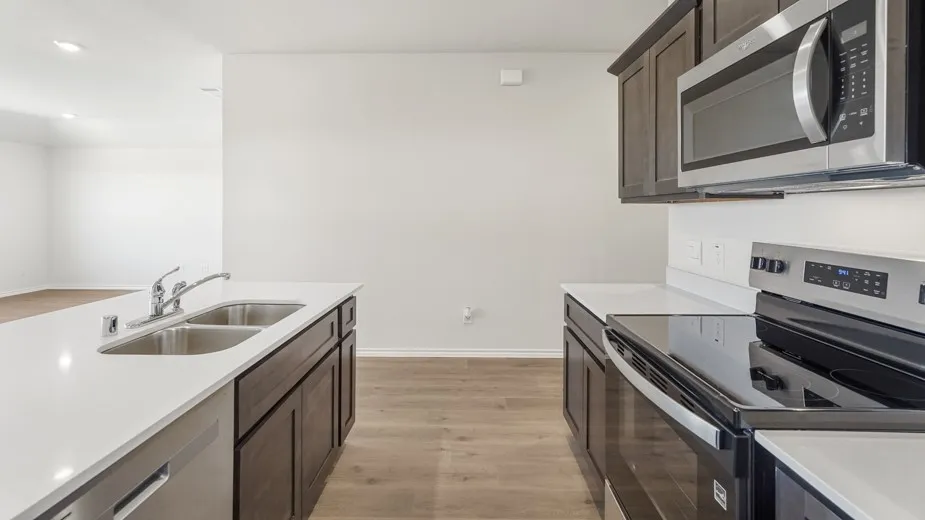Contemporary kitchen featuring dark wood-finish cabinetry, stainless steel appliances, a double basin sink, and wood-finish flooring