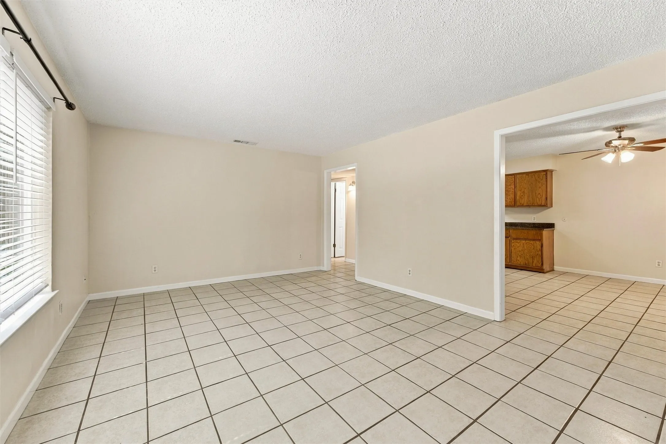 Spacious room featuring neutral wall paint, white tile flooring, and a window with blinds