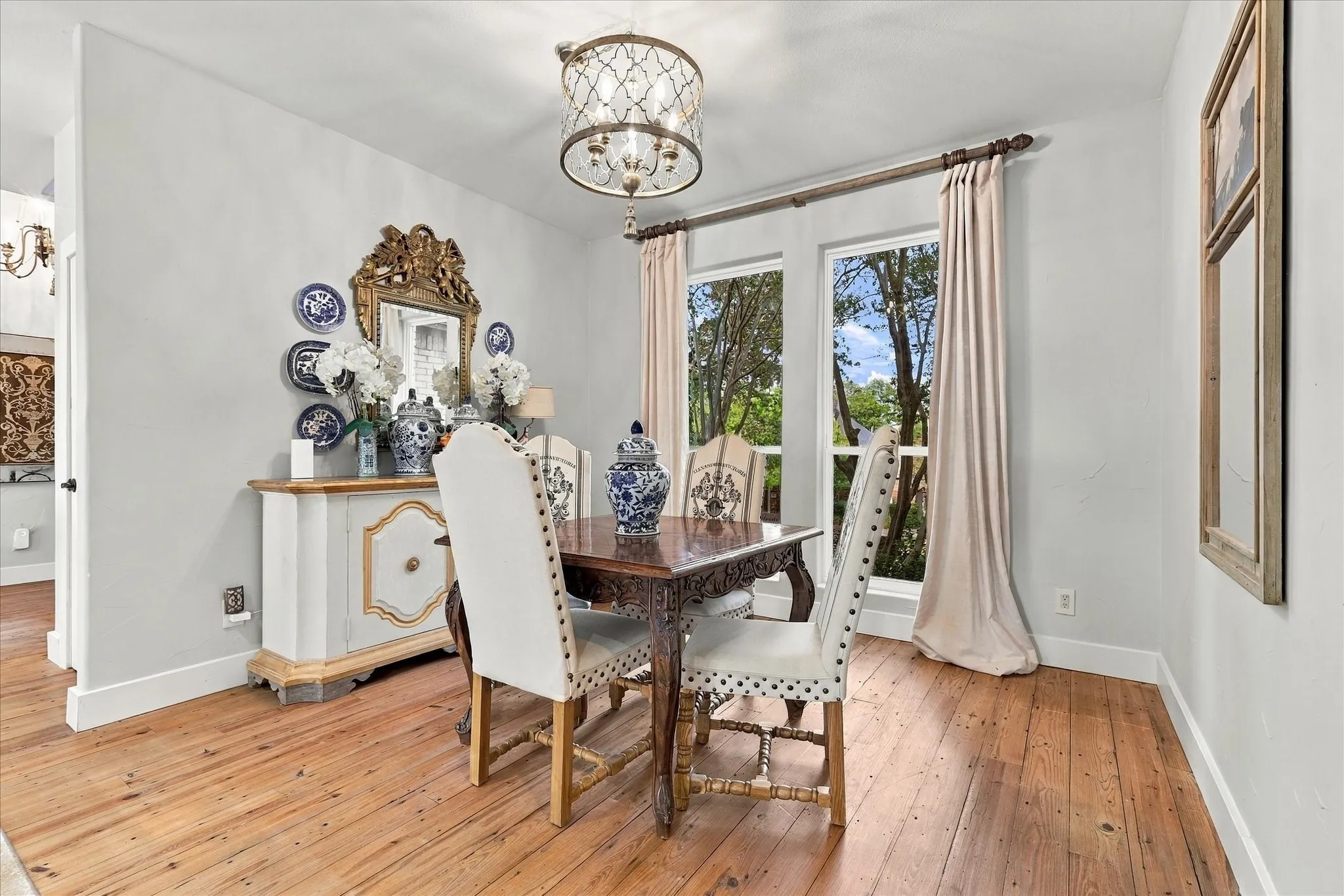 Dining area adjacent to kitchen featuring wood floors, new lighting fixture and custom drapes that convey with home.