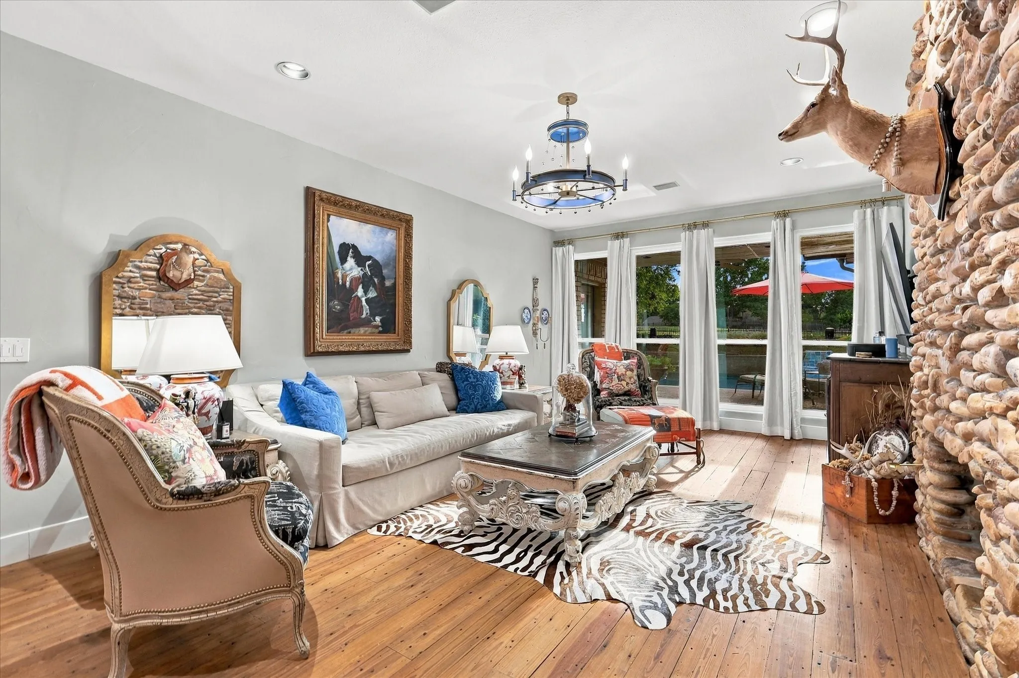 Living area overlooking backyard pool area, custom stone gas fireplace, wood floors &  new can lighting. All windows throughout the home have been replaced.