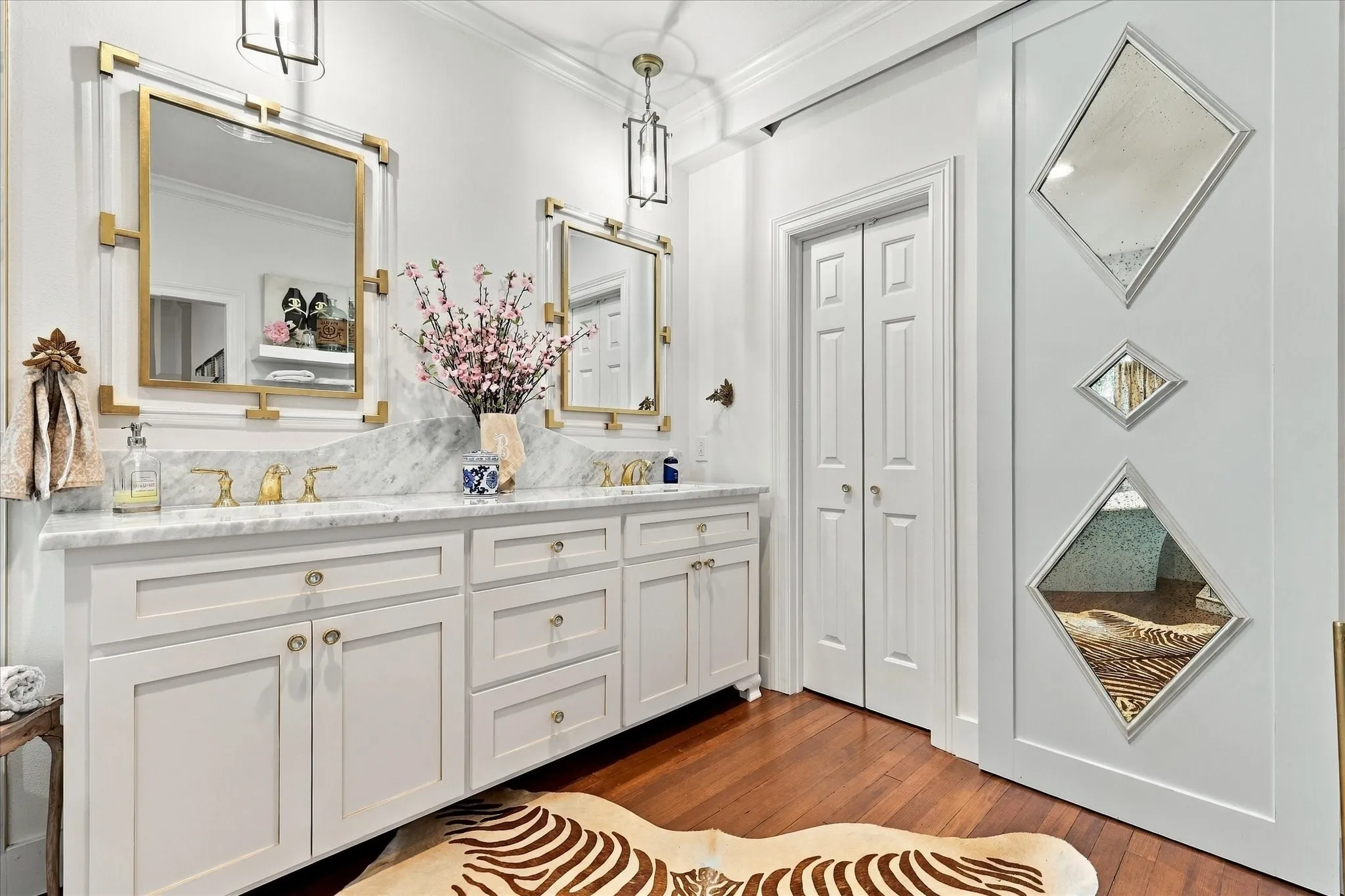Primary bathroom includes new cabinets with dual sinks, new countertops, designer lighting and plumbing fixtures and wood flooring.