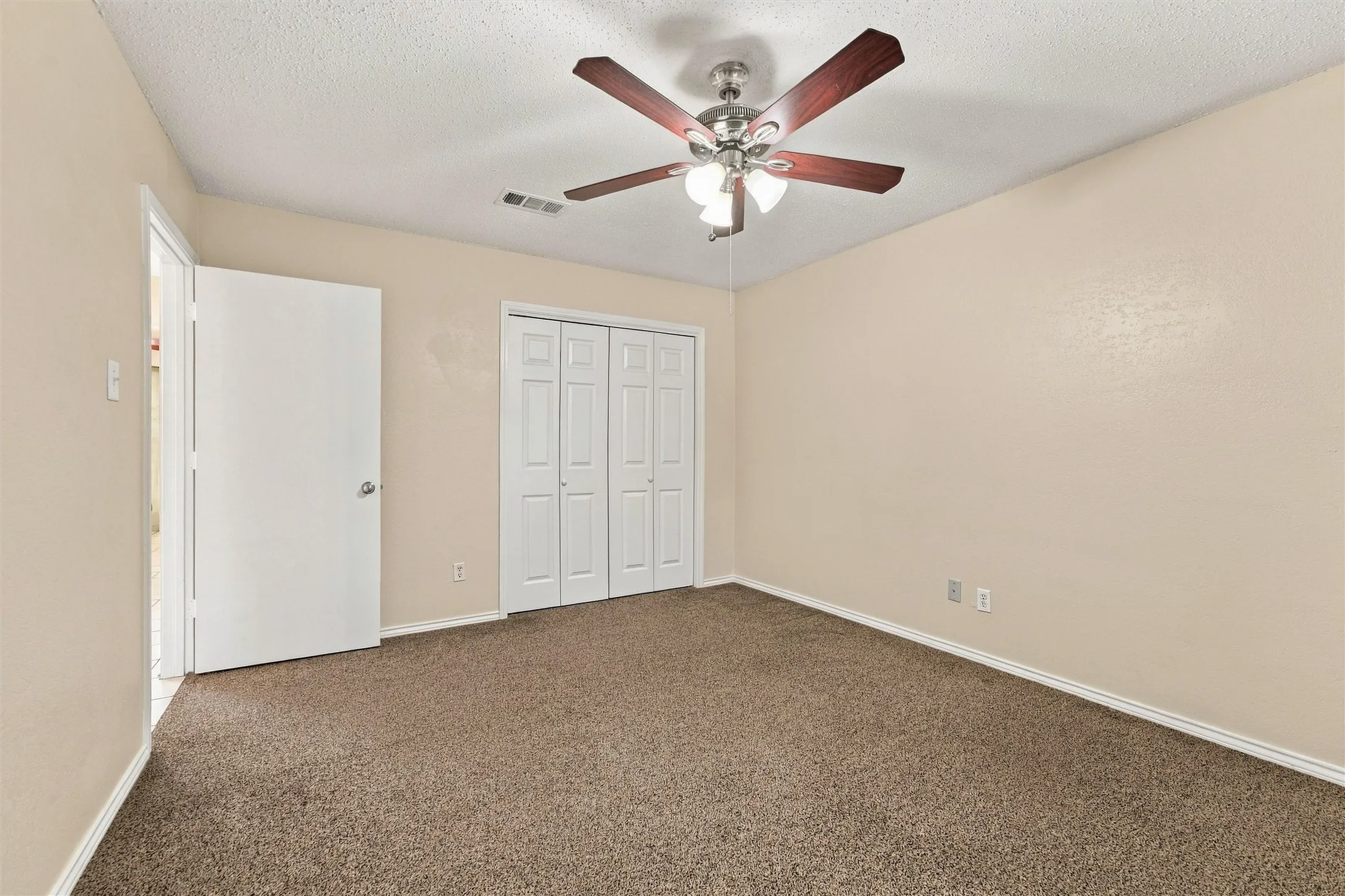 Ceiling fan with light fixture, neutral carpet flooring, bi-fold closet doors, and painted walls