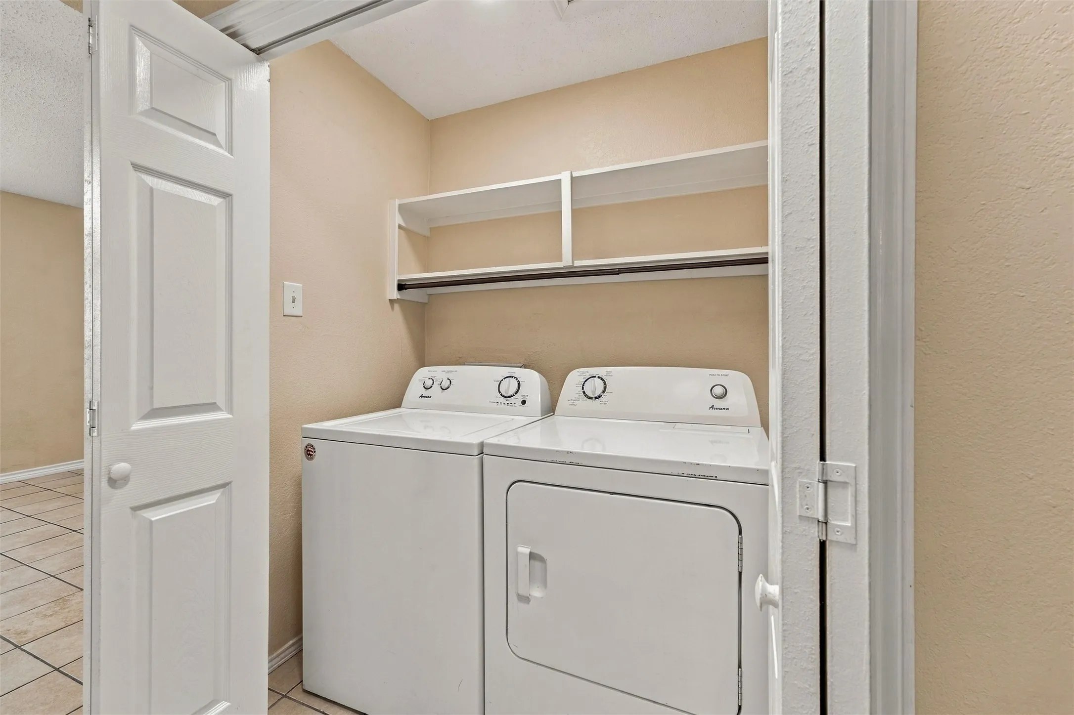 Built-in laundry appliances with a storage shelf and hanging rod, complemented by neutral wall tones
