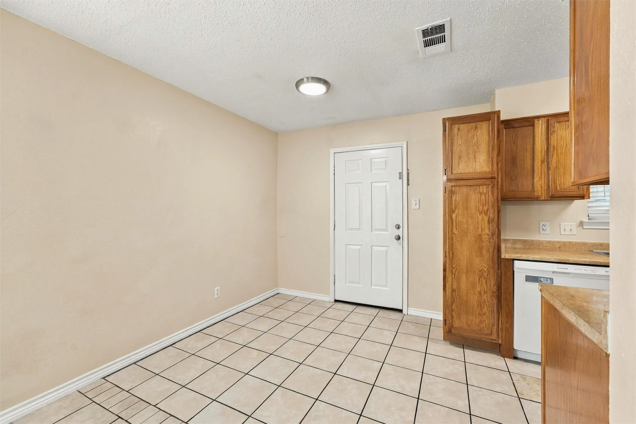Tile flooring, wood-finish cabinetry, and a built-in dishwasher