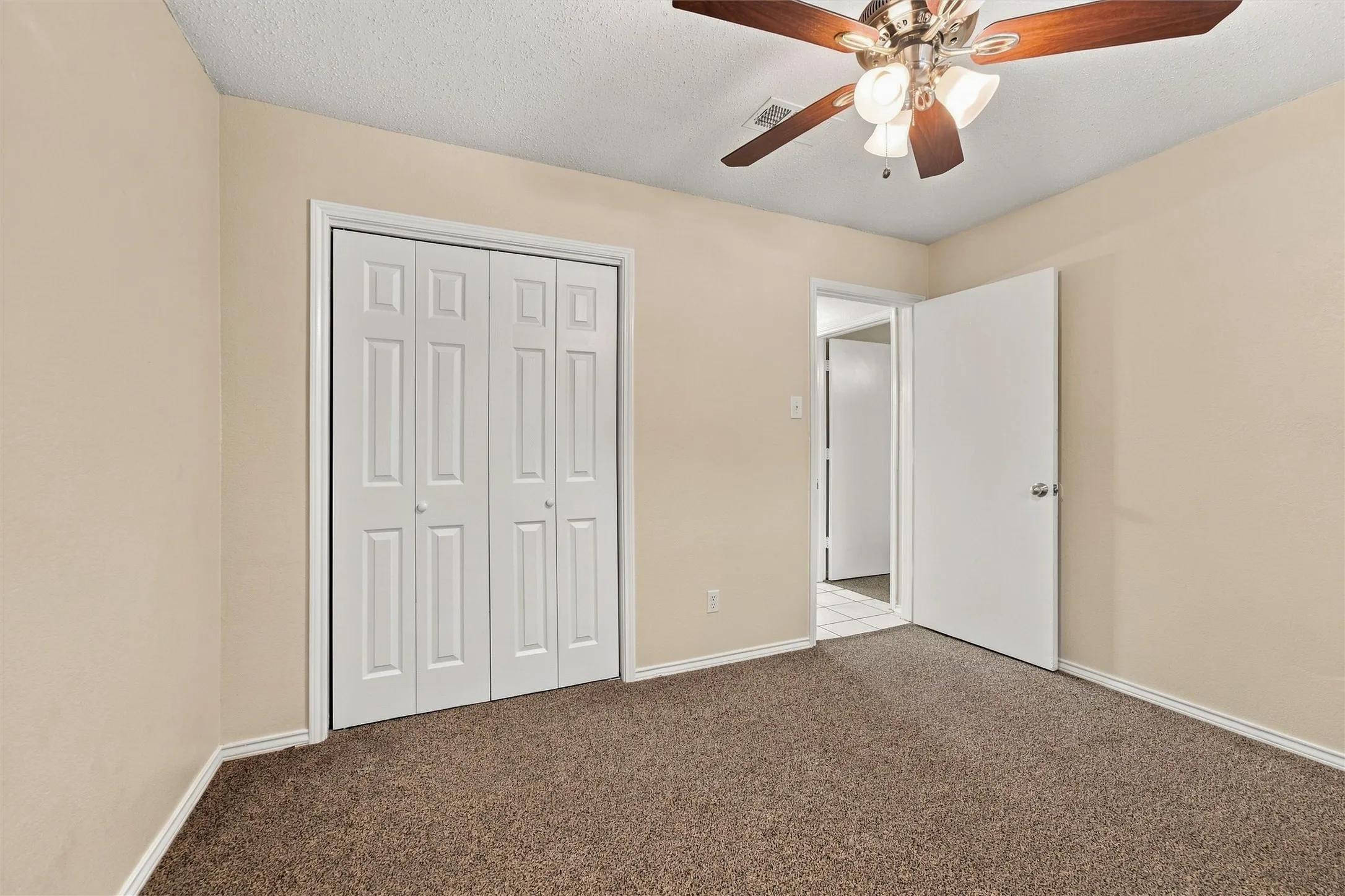 Neutral wall tones, brown carpet flooring, bi-fold closet doors, and a ceiling fan with integrated lighting