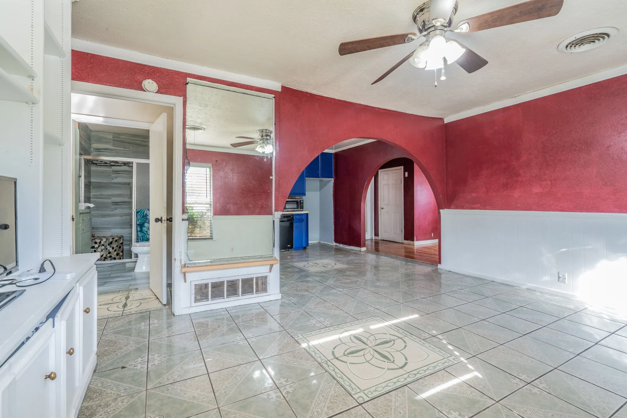 Tile flooring with an integrated decorative pattern, a ceiling fan, and arched doorways