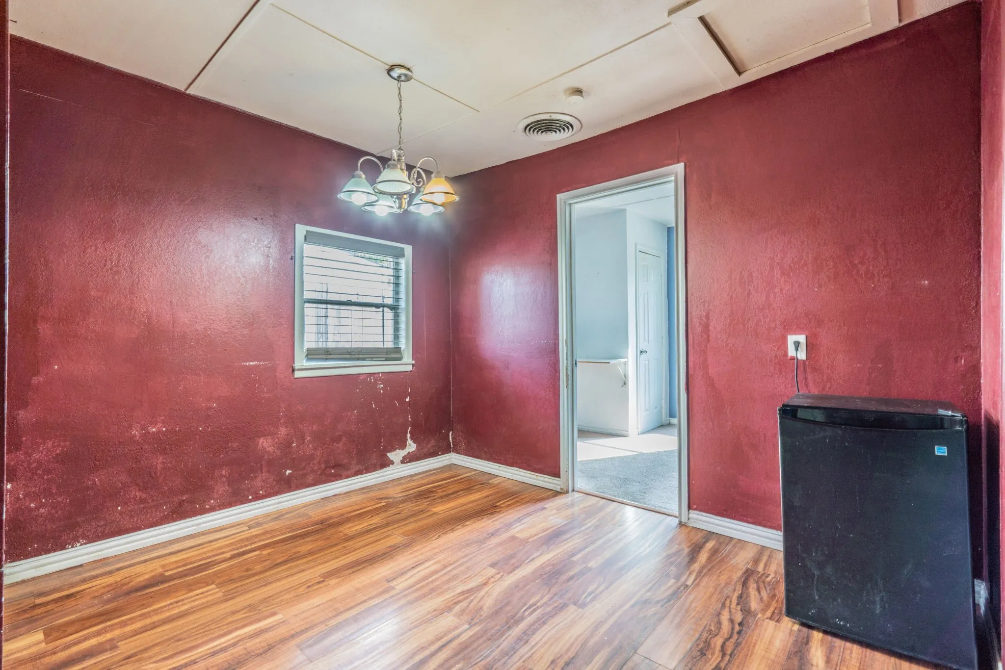 Wood-finish flooring with baseboard trim, complemented by an overhead multi-bulb light fixture