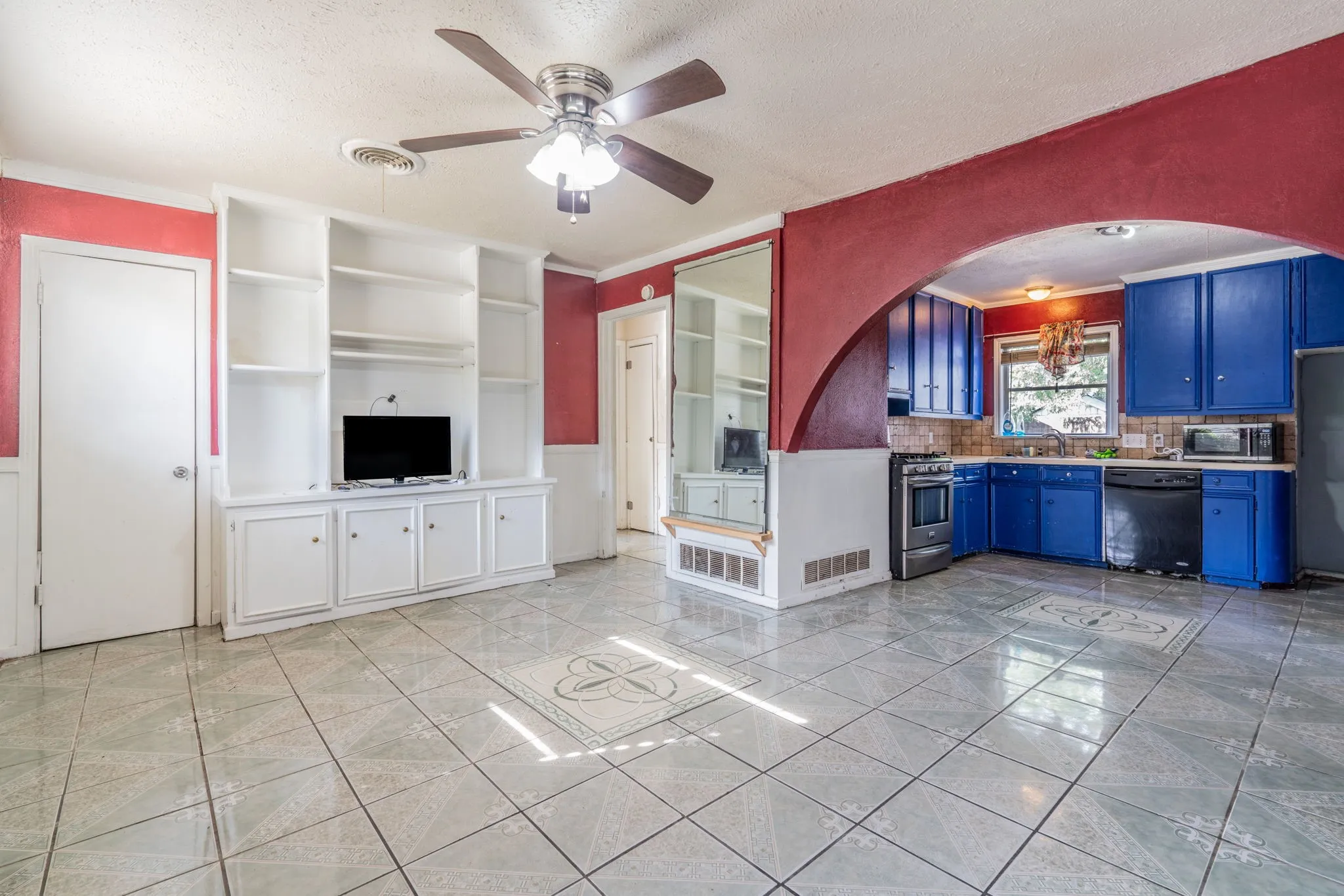 Built-in shelving and cabinetry, ceiling fan, tile flooring, kitchen with blue cabinetry, and stainless steel range