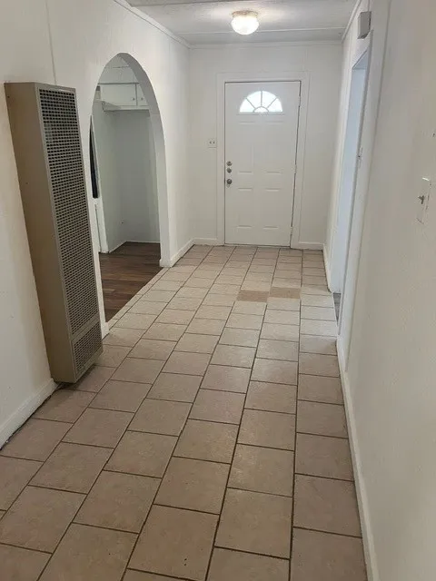 Tiled entryway with a white paneled door featuring a half-moon window