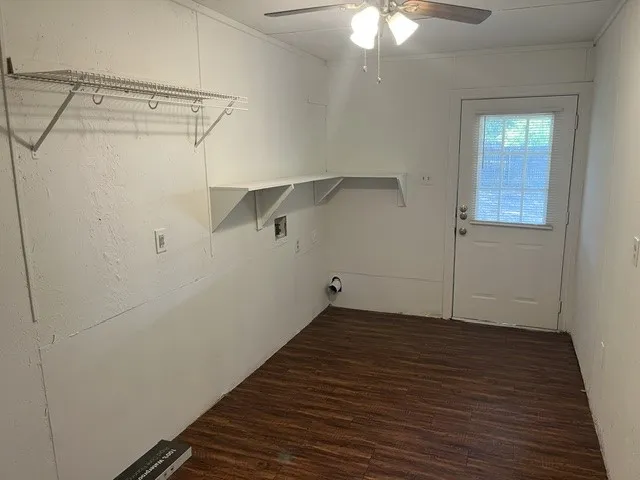 Utility room featuring wood-finish flooring, a ceiling fan with integrated lighting, wall-mounted shelving, and a rear exterior door with a window pane