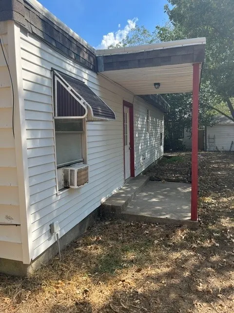 Exterior siding with an attached window awning and a covered patio supported by a red pillar