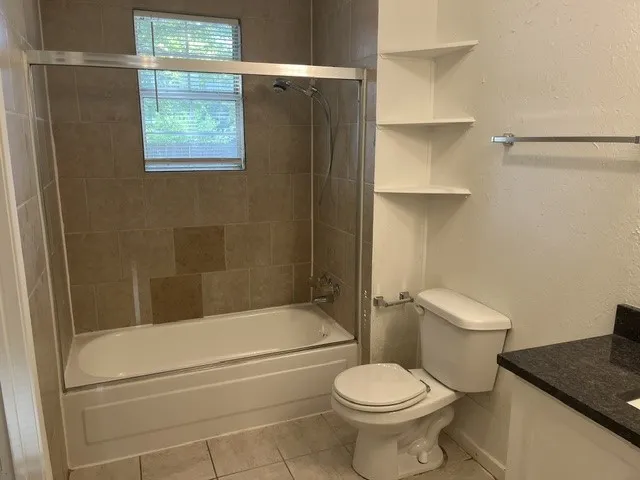 Bathtub with tile surround, glass shower enclosure, and built-in corner shelving