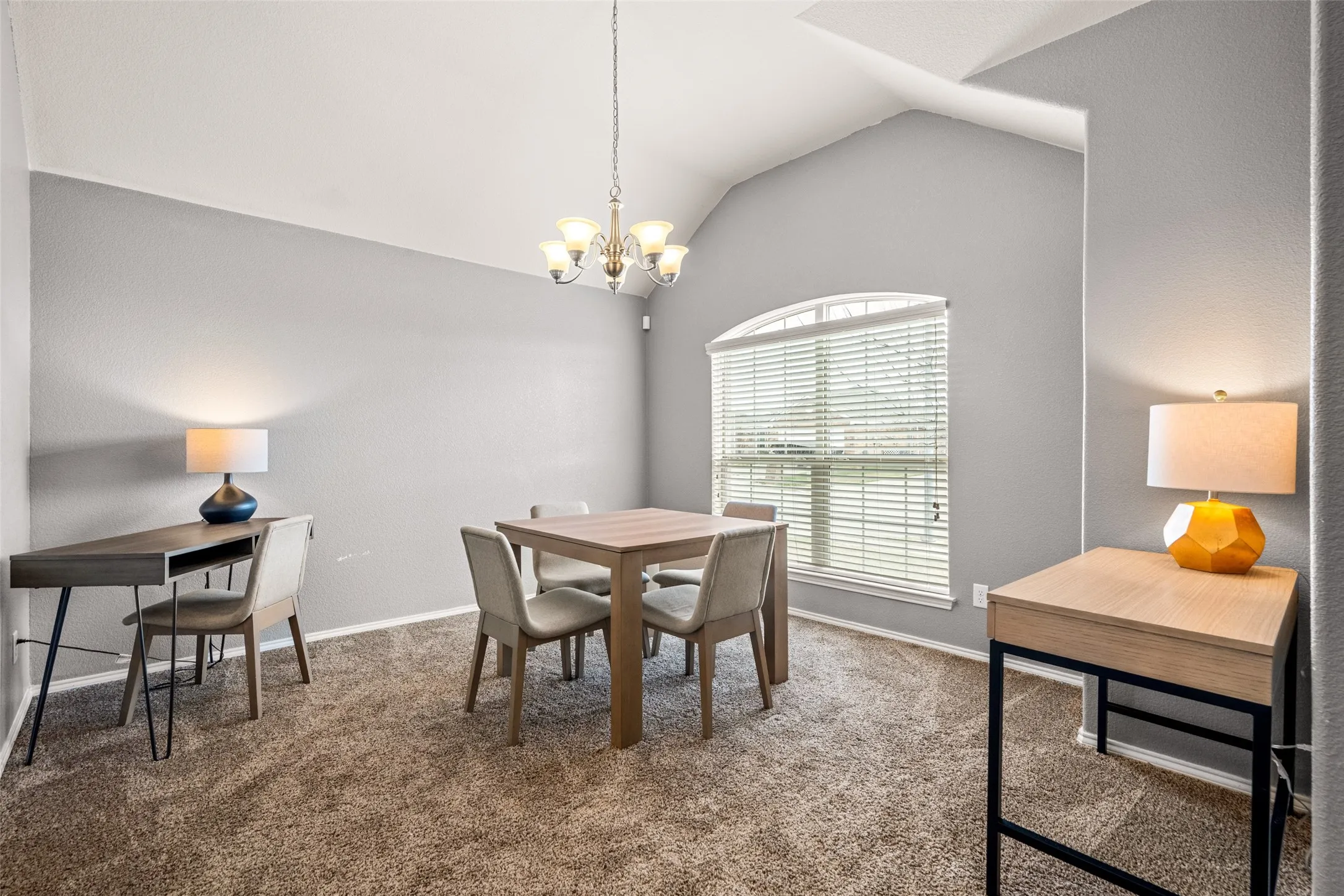 Vaulted ceiling, arched window with blinds, and a chandelier