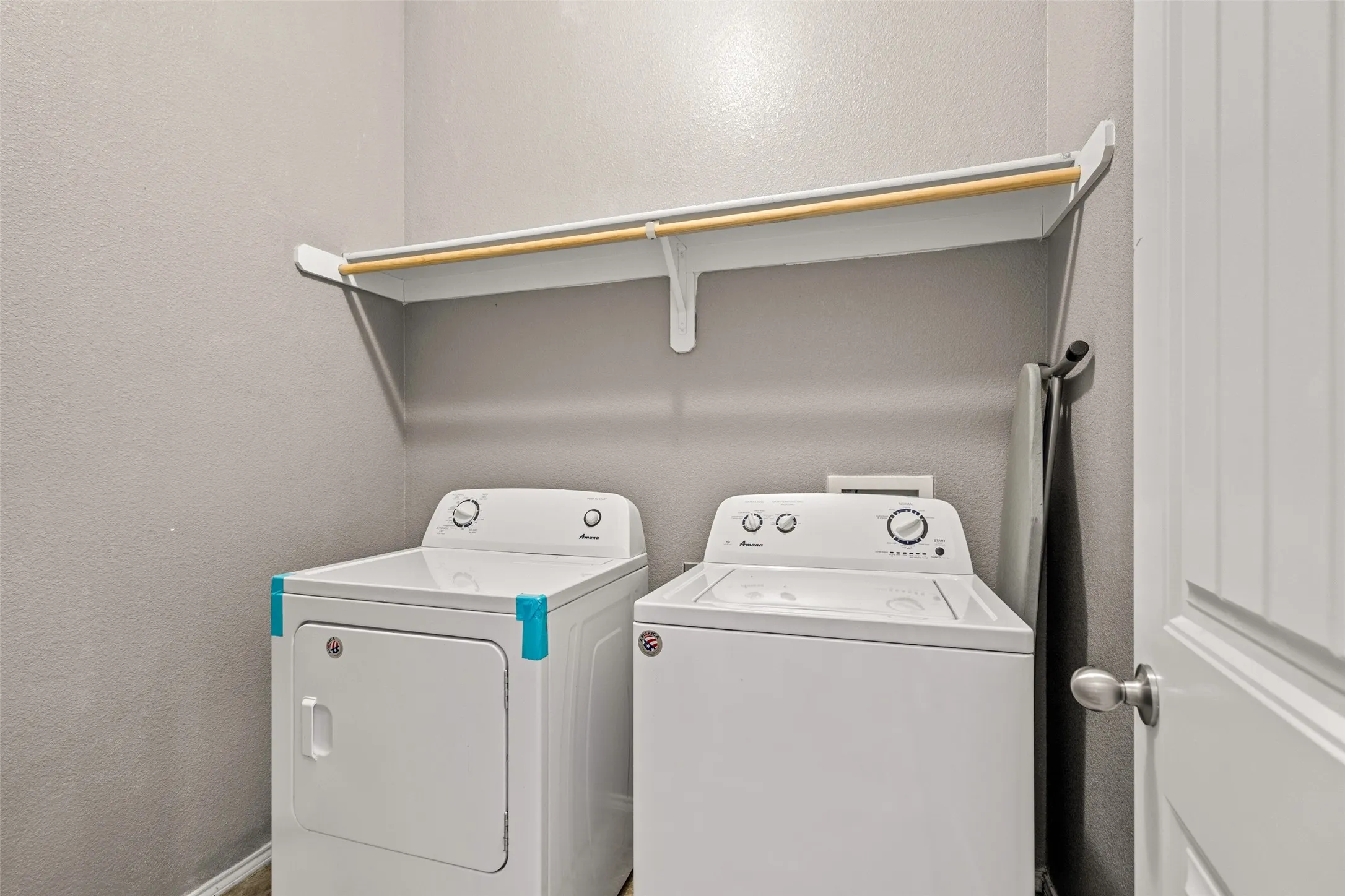 Laundry area featuring a built-in white shelf with a hanging rod