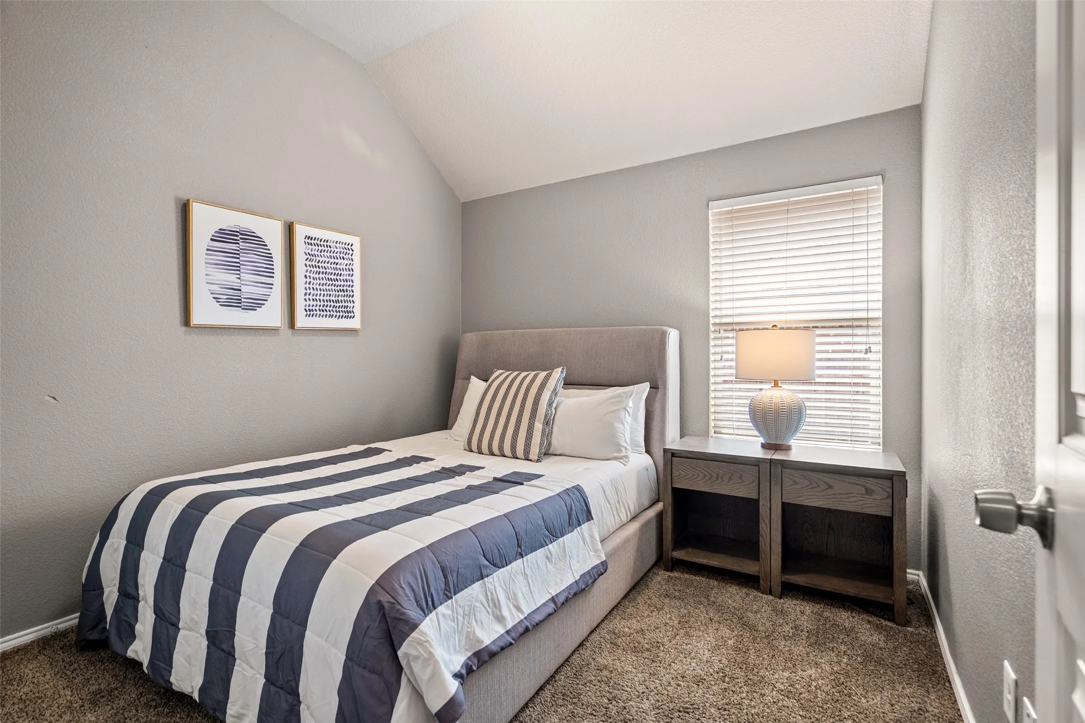 Vaulted ceiling, window with blinds, and durable carpeting