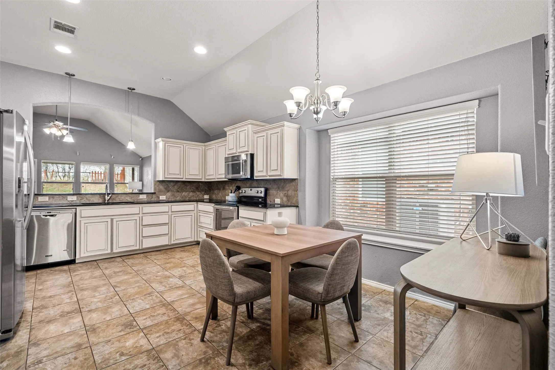 Kitchen featuring white cabinetry, stainless steel appliances, dark countertops, and tile flooring